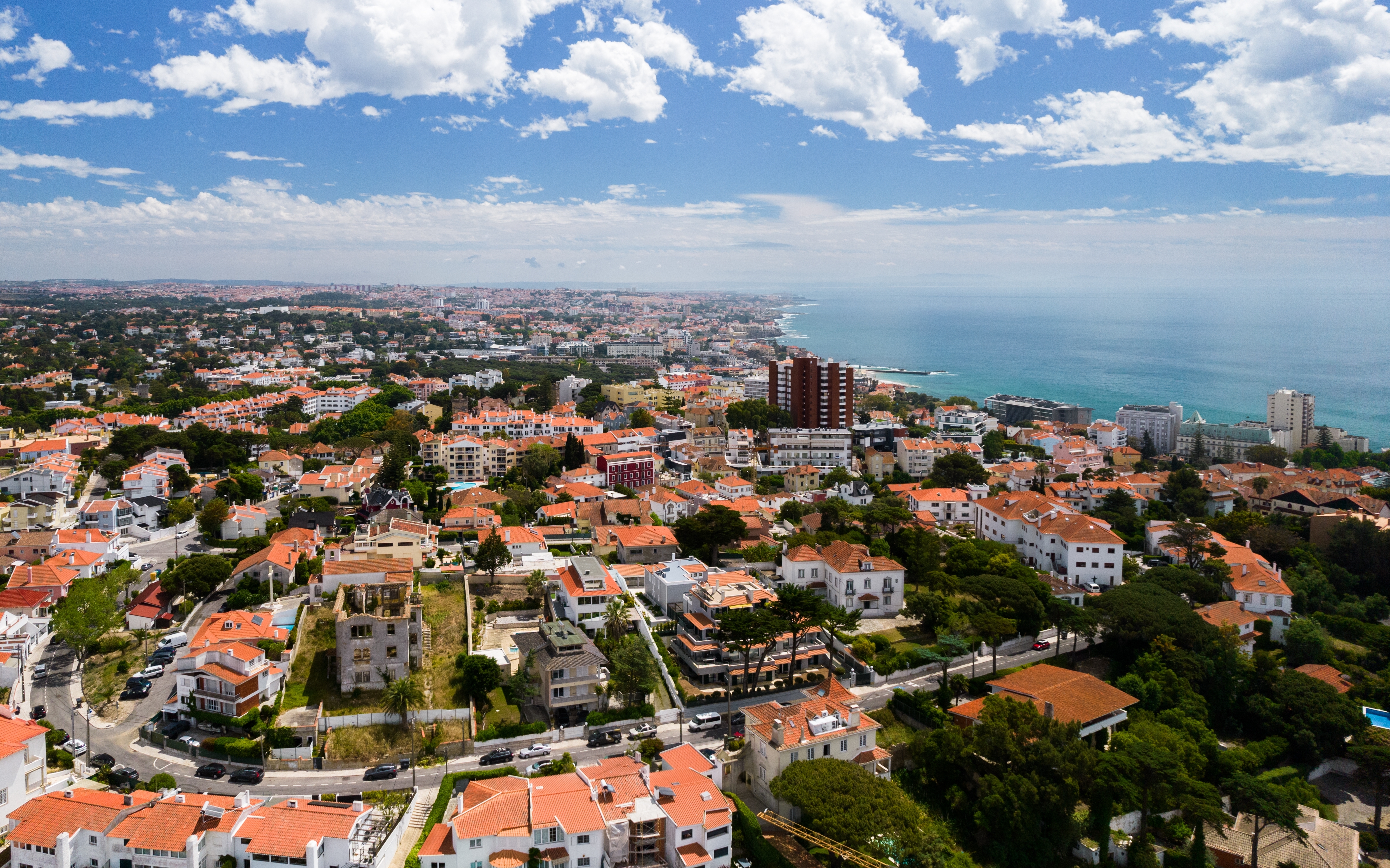 Luftfoto af den charmerende kystby Estoril nær Lissabon med hvide huse, røde tage og udsigt over Atlanterhavet