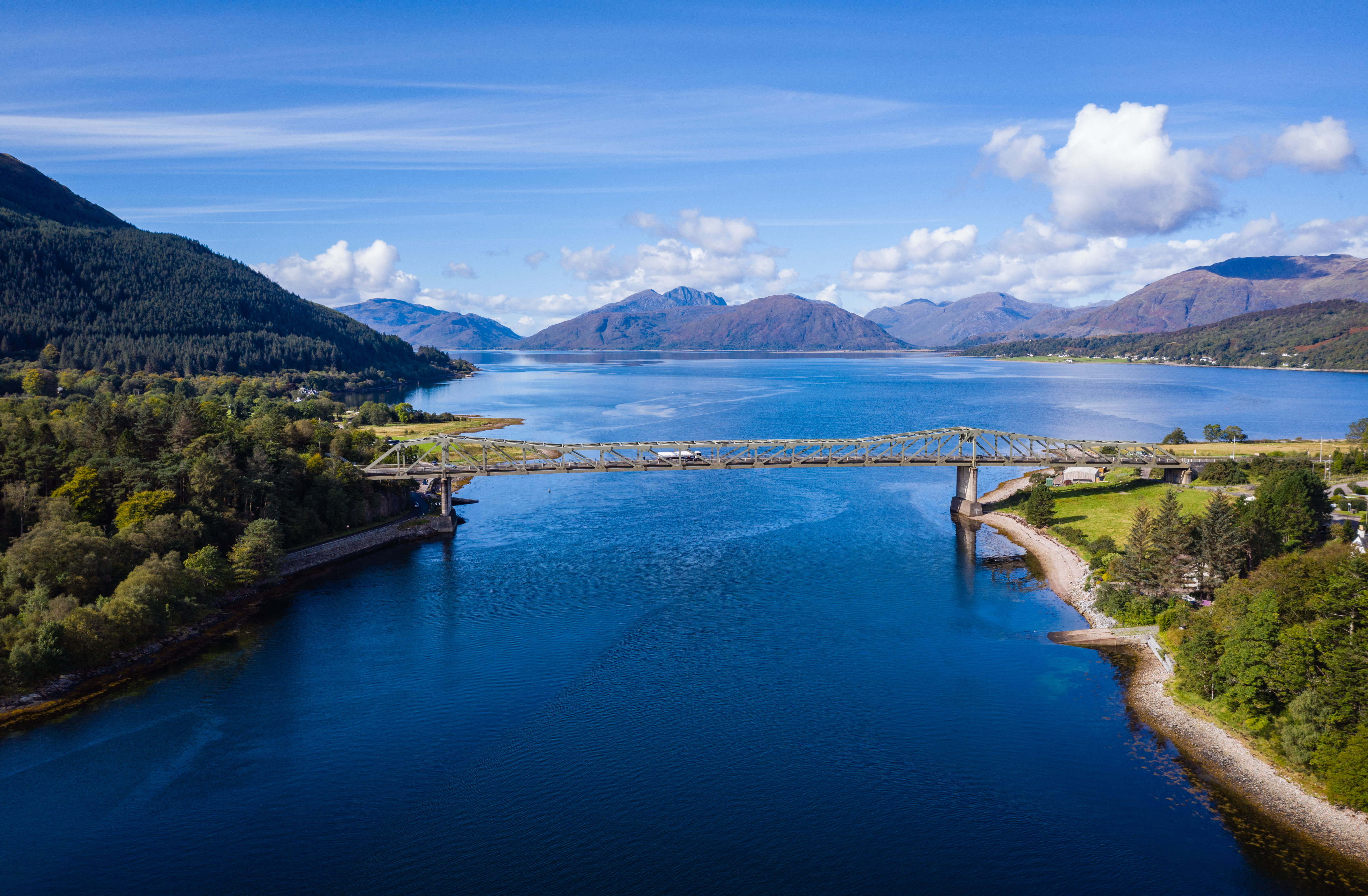 Imponerende luftperspektiv over Loch Linnhe nær Glencoe i de skotske højlande med blåt fjordvand, grøn kystlinje og bjergrige omgivelser på en klar sommerdag