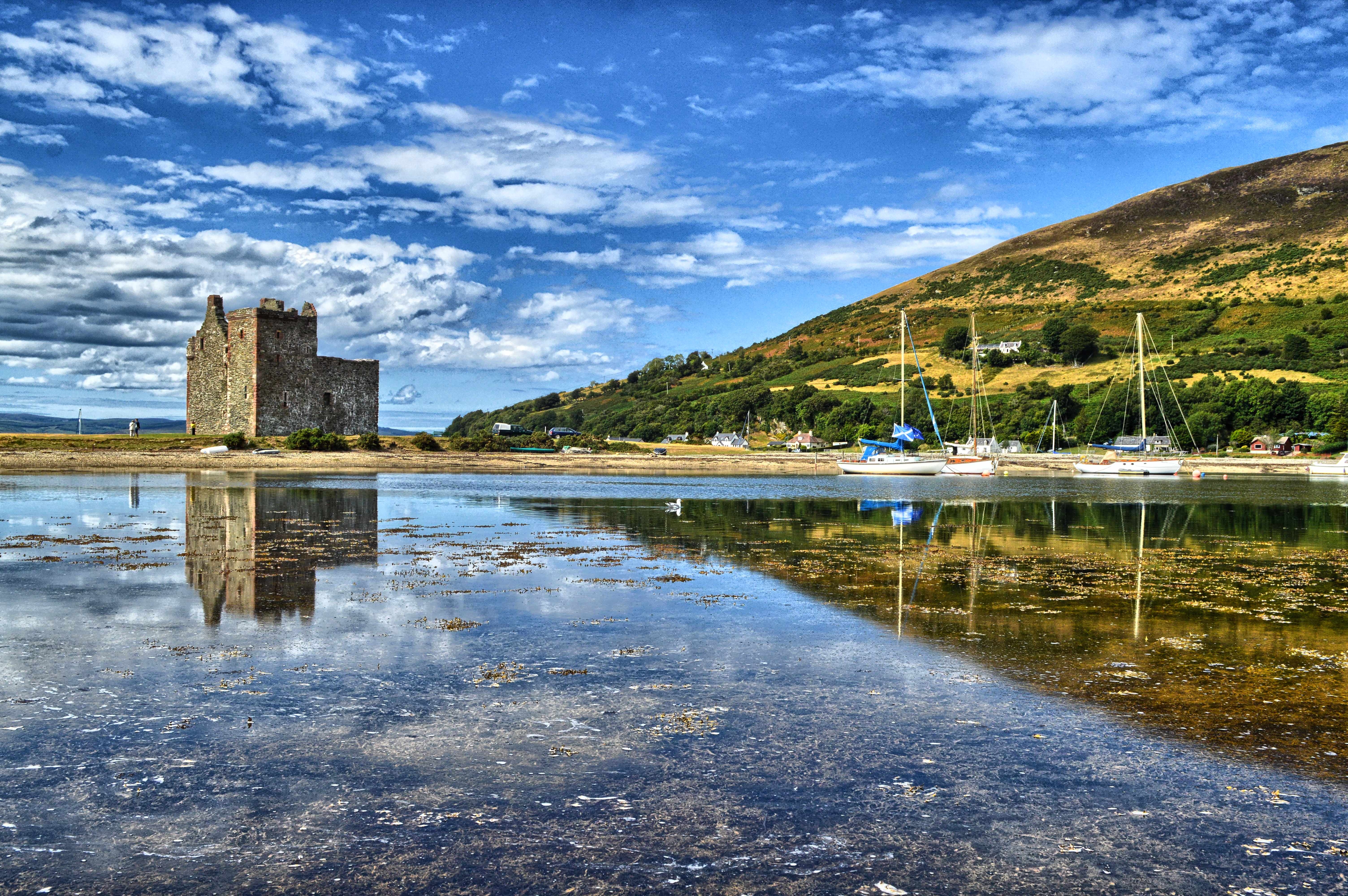 Middelalderborgen Lochranza Castle på Isle of Arran i Skotland med smukt spejlbillede i den stille loch