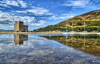 Middelalderborgen Lochranza Castle på Isle of Arran i Skotland med smukt spejlbillede i den stille loch