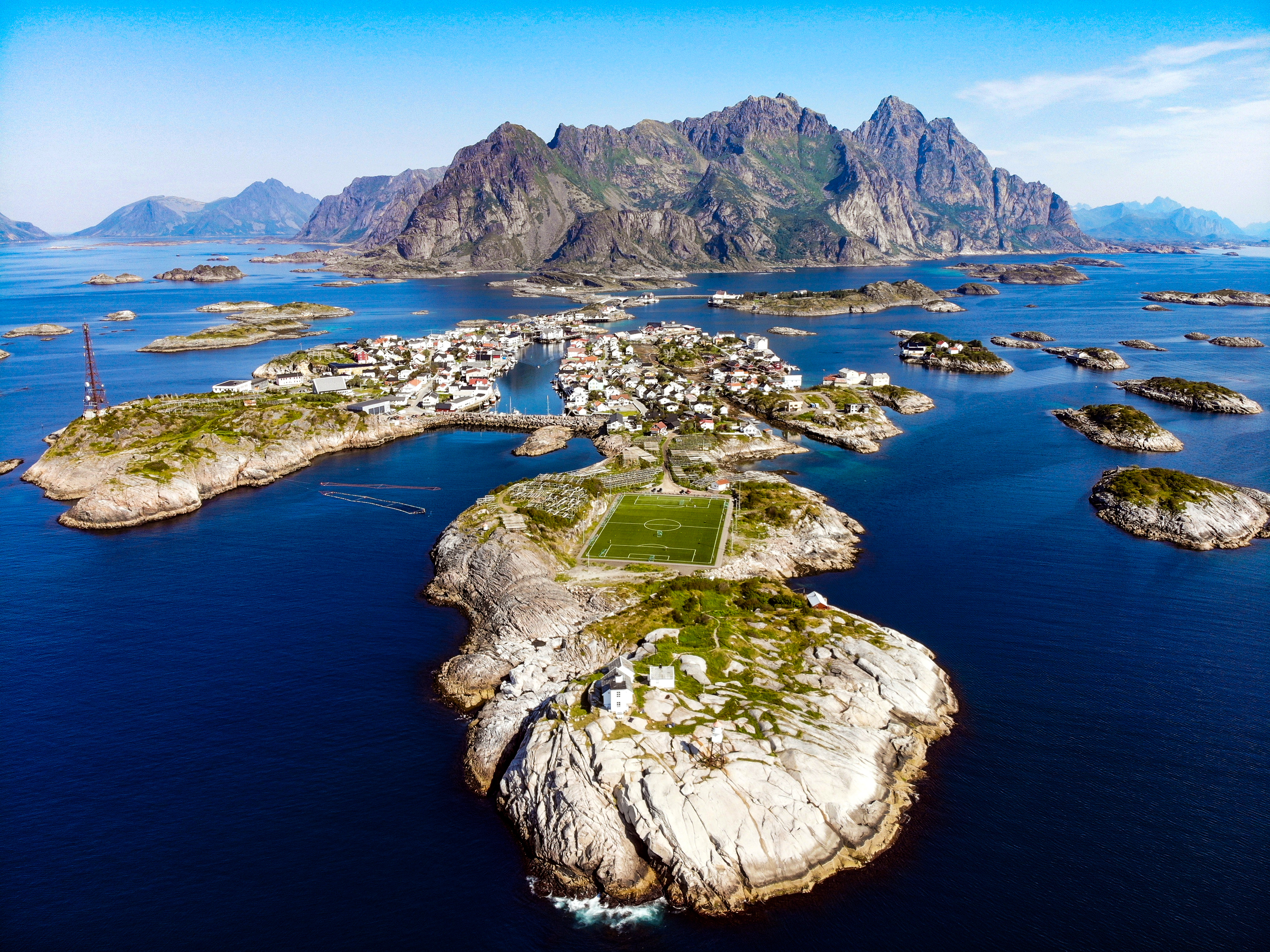 Luftbillede af Henningsvær fiskelandsby i Lofoten med imponerende bjerge og krystalklart vand omkring øerne