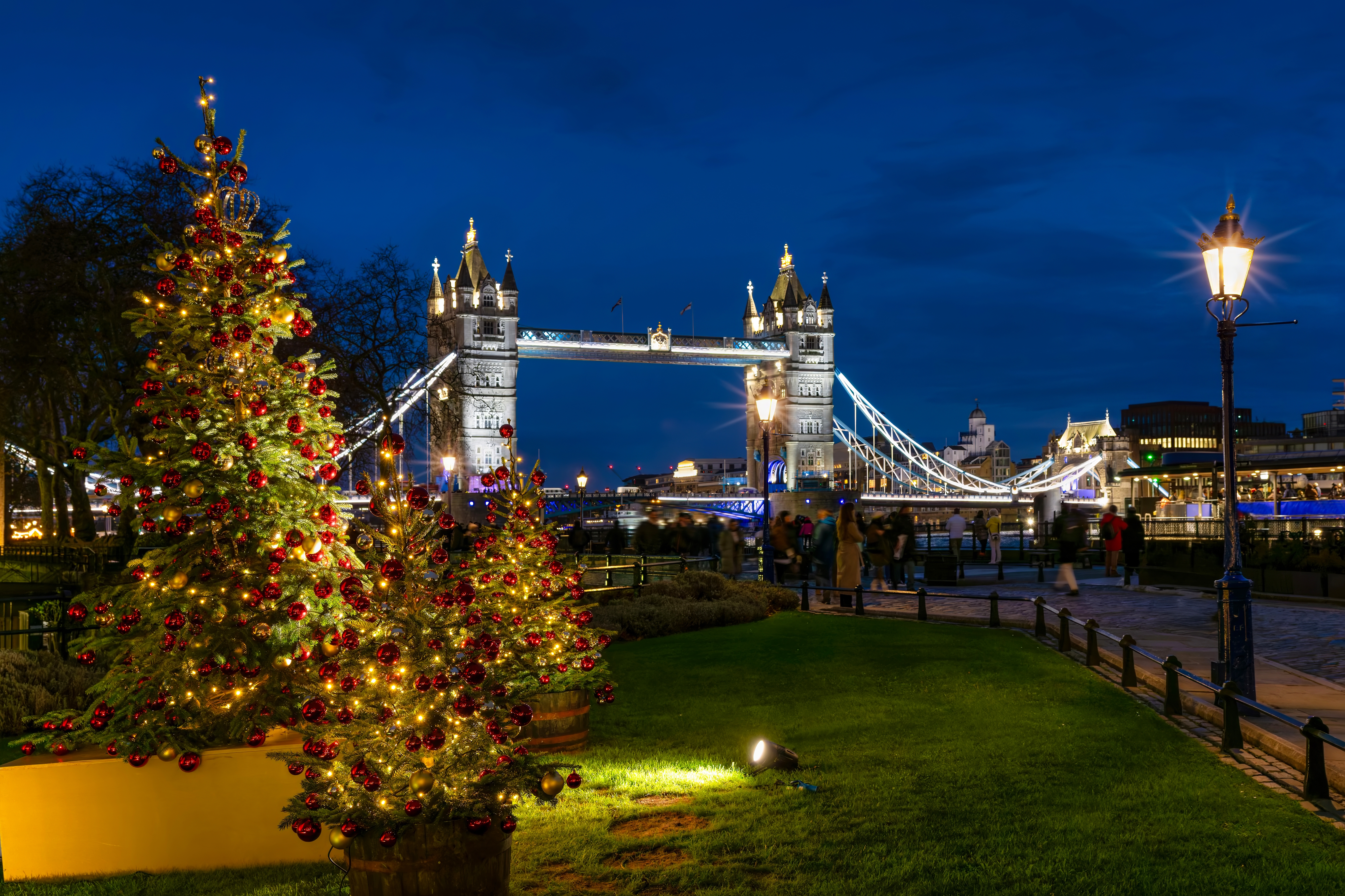 Juletræ pyntet med røde og gyldne kugler foran Tower Bridge i London på en smuk vinternes aften