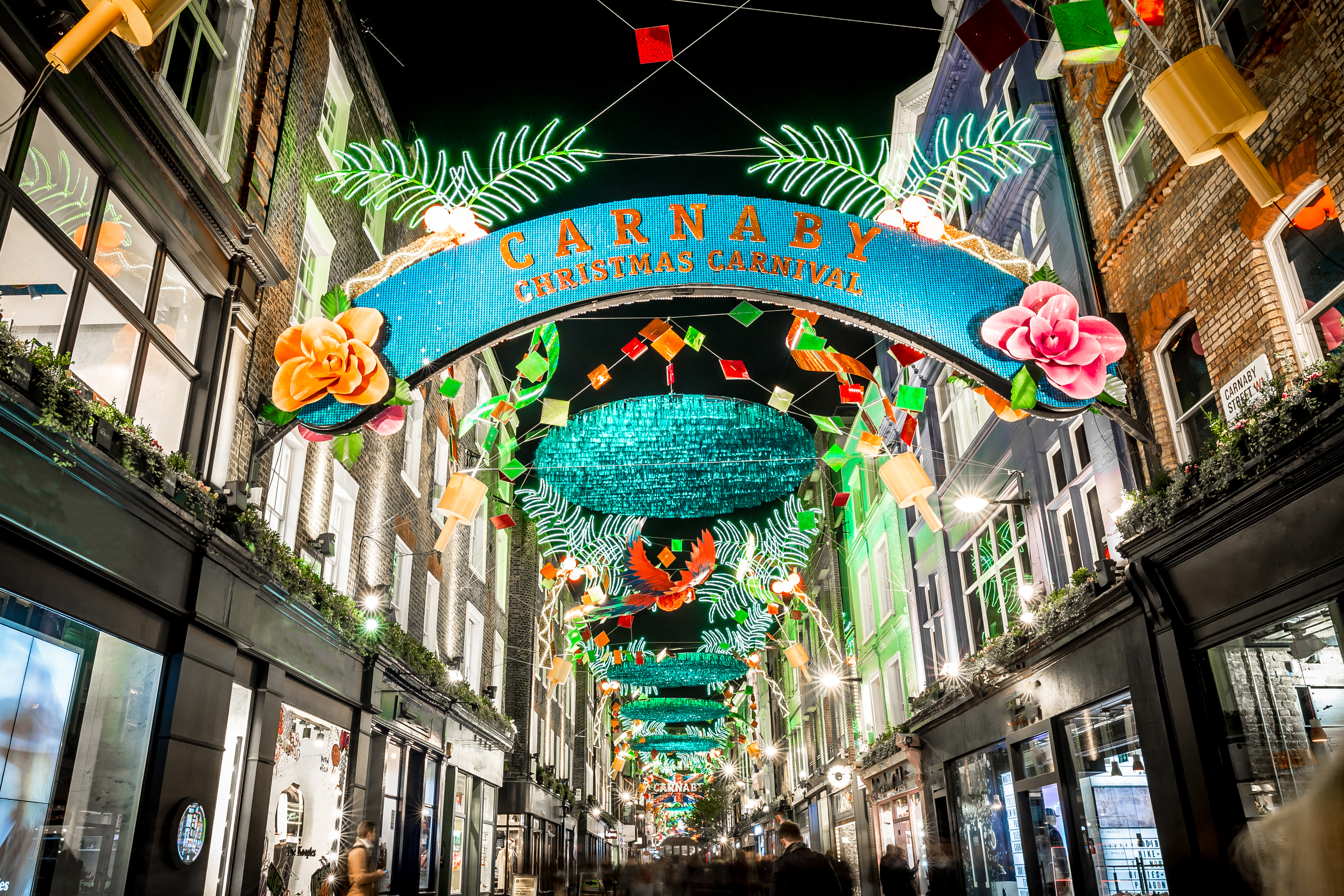 Spektakulært lysshow på Carnaby Street i London med Christmas Carnaby banner og tropiske julelys