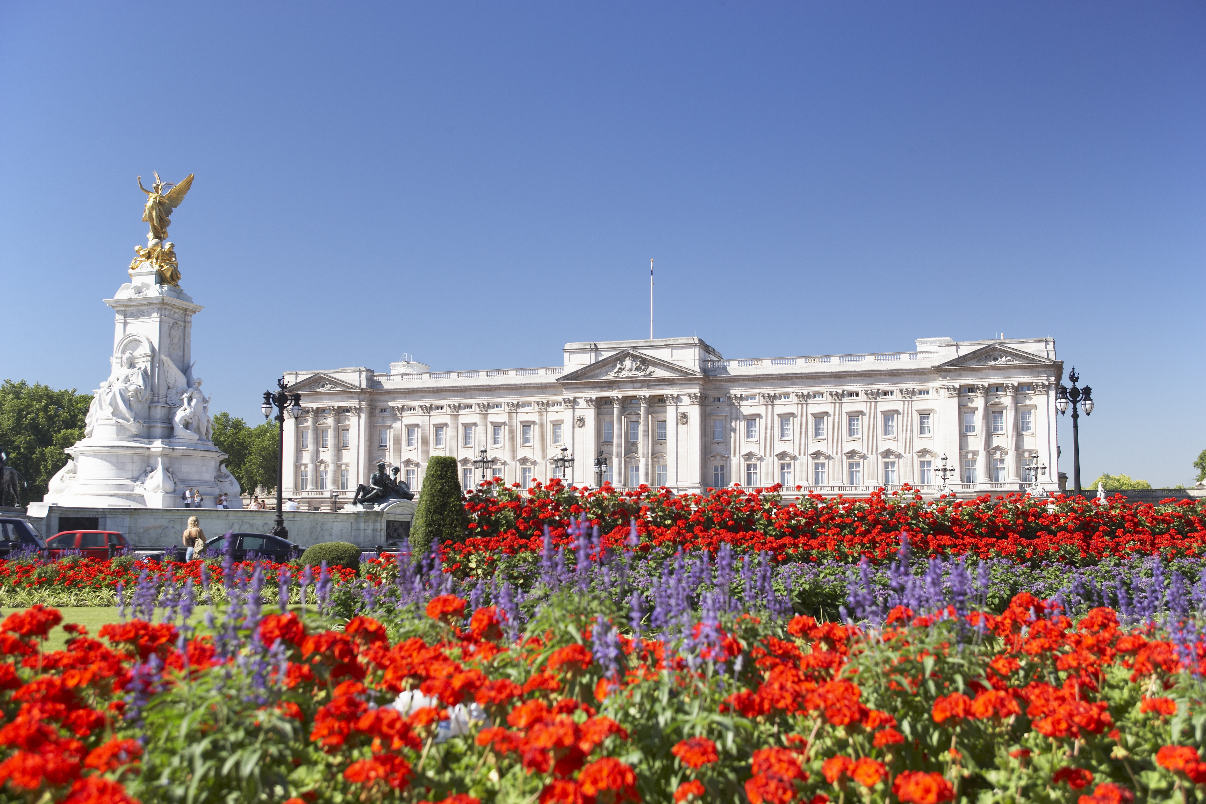 Buckingham Palace, den britiske monarks officielle residens i London, fotograferet på en solskinsdag med farvestrålende blomsterbede i Queens Garden og den karakteristiske palæfacade