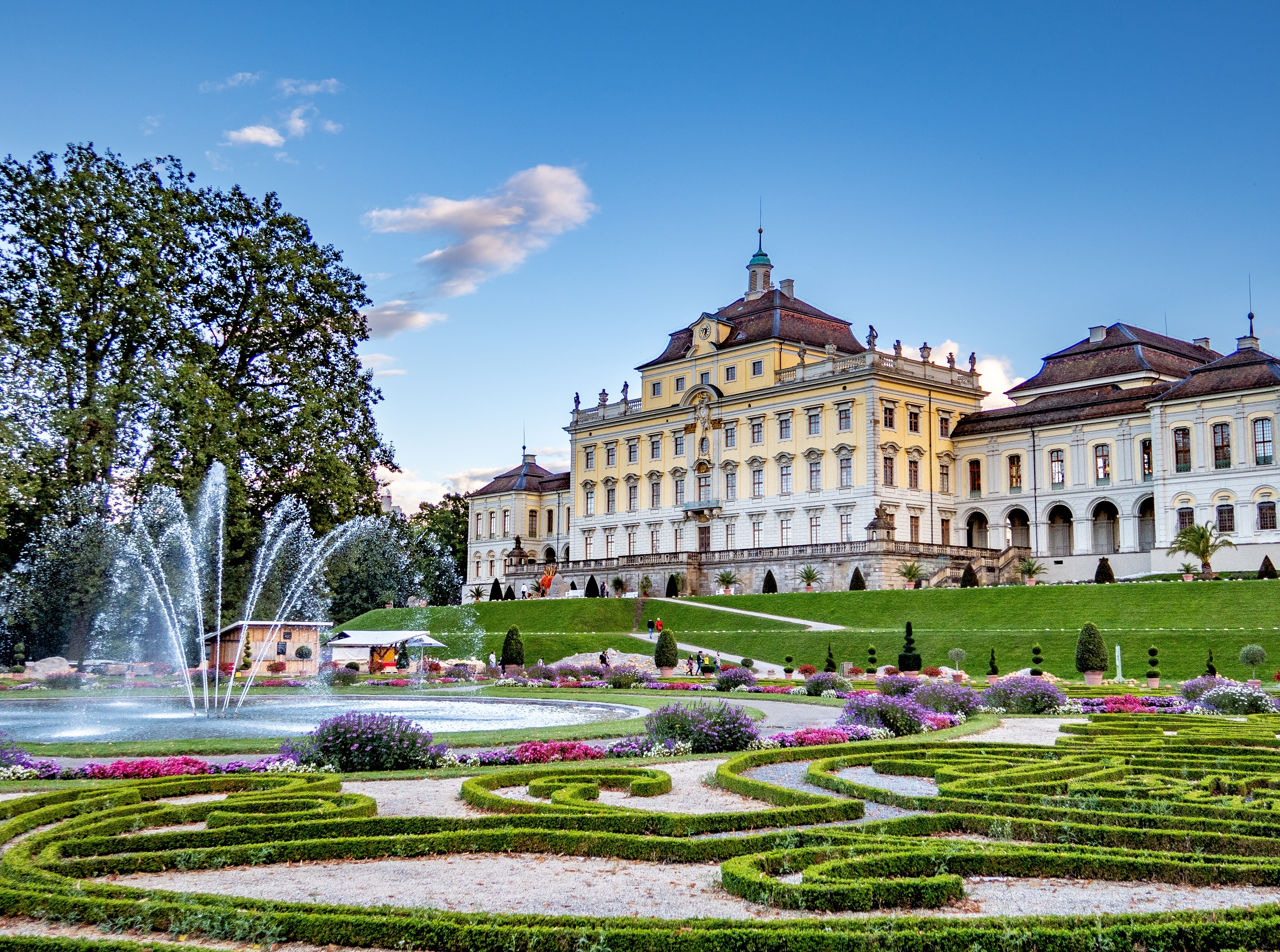 Imponerende udsigt over Ludwigsburg Slots barokhaver i Tyskland med springvand, blomsterbed og den gule slotsbygning