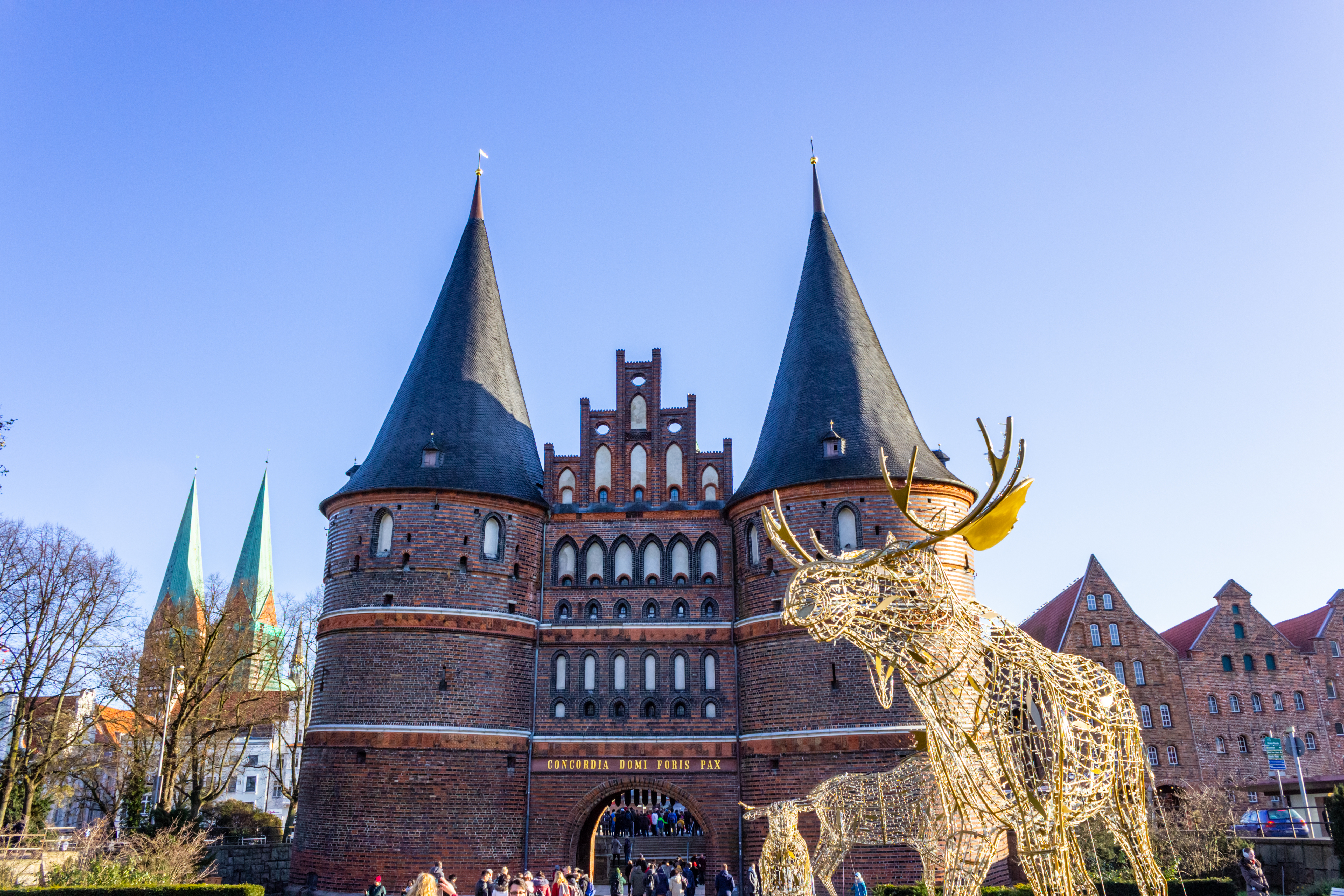 Vinterlig stemning ved Holsten Porten i Lübeck med gylden rensdyrsdekoration og solrig blå himmel