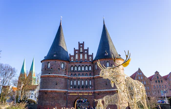 Vinterlig stemning ved Holsten Porten i Lübeck med gylden rensdyrsdekoration og solrig blå himmel