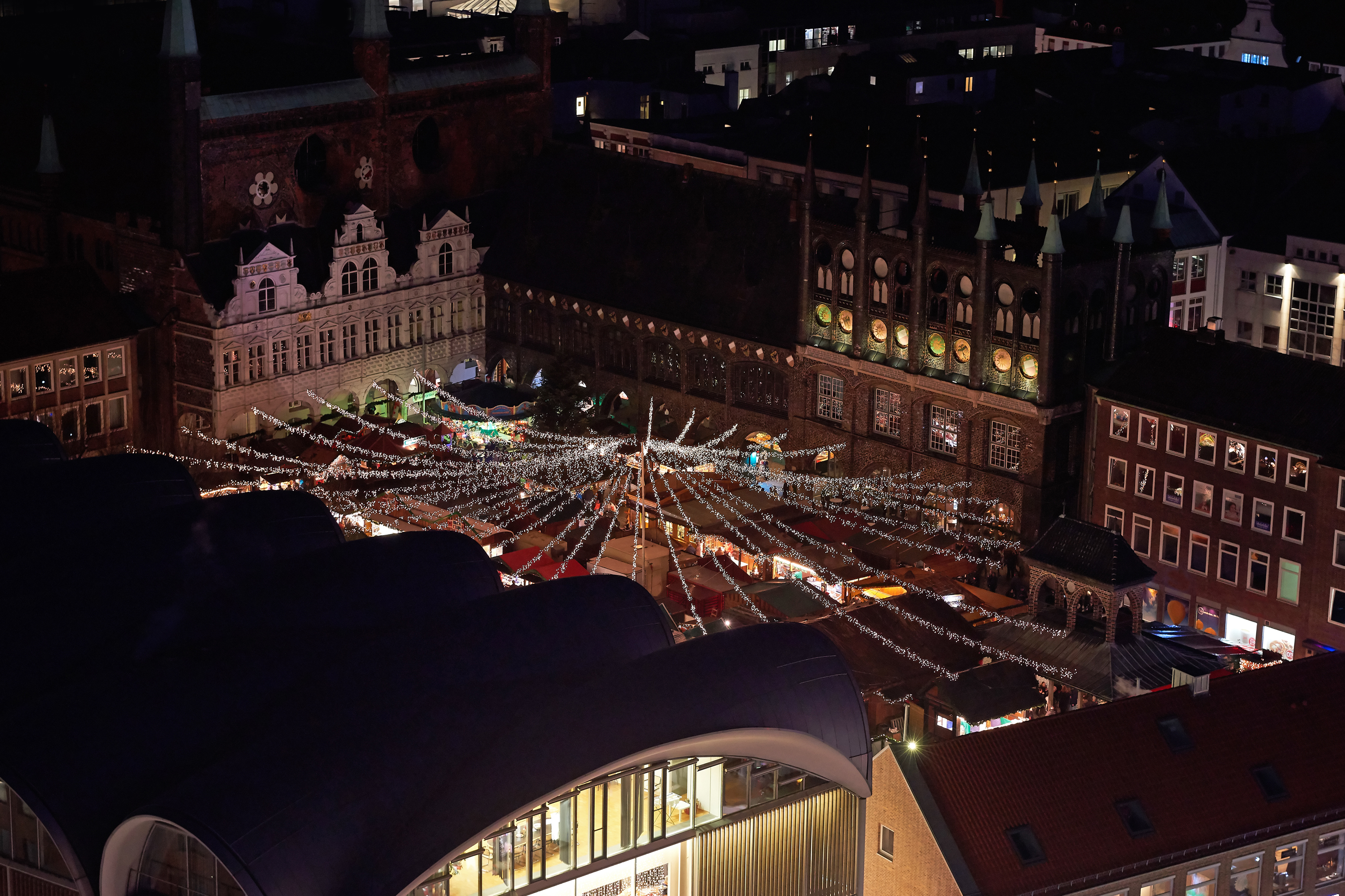 Luftfoto af det festlige julemarked i Lübeck om natten med imponerende lysdekoration og historiske bygninger i Tyskland