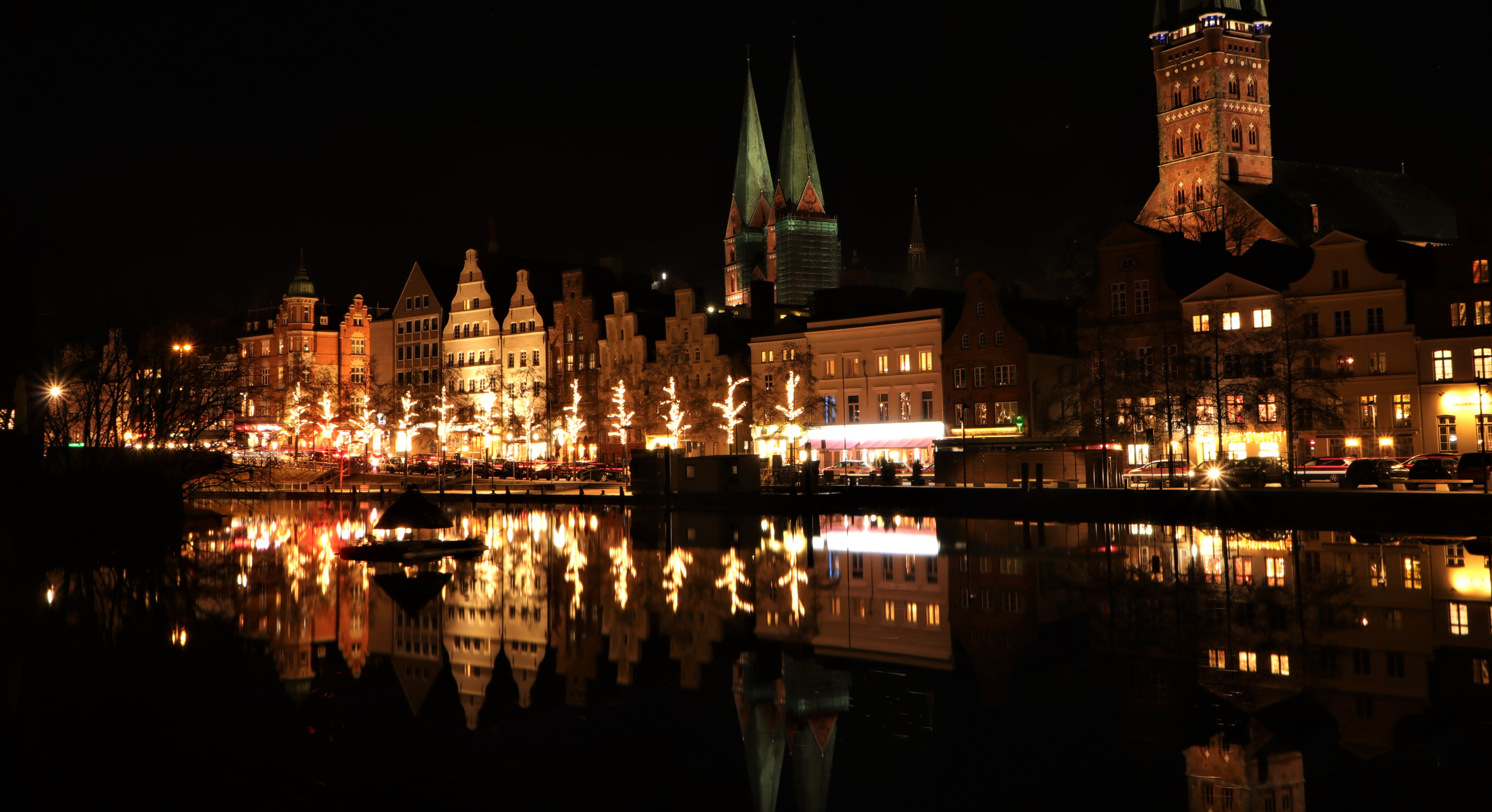 UNESCO-verdensarv Lübeck om natten med oplyste hanseatiske gavlhuse og kirkespir reflekteret i Trave-floden