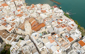 Smukt luftfoto af Vieste i det sydlige Italien med tæt liggende hvide huse, terrakottatage og en imponerende katedral ud mod havet