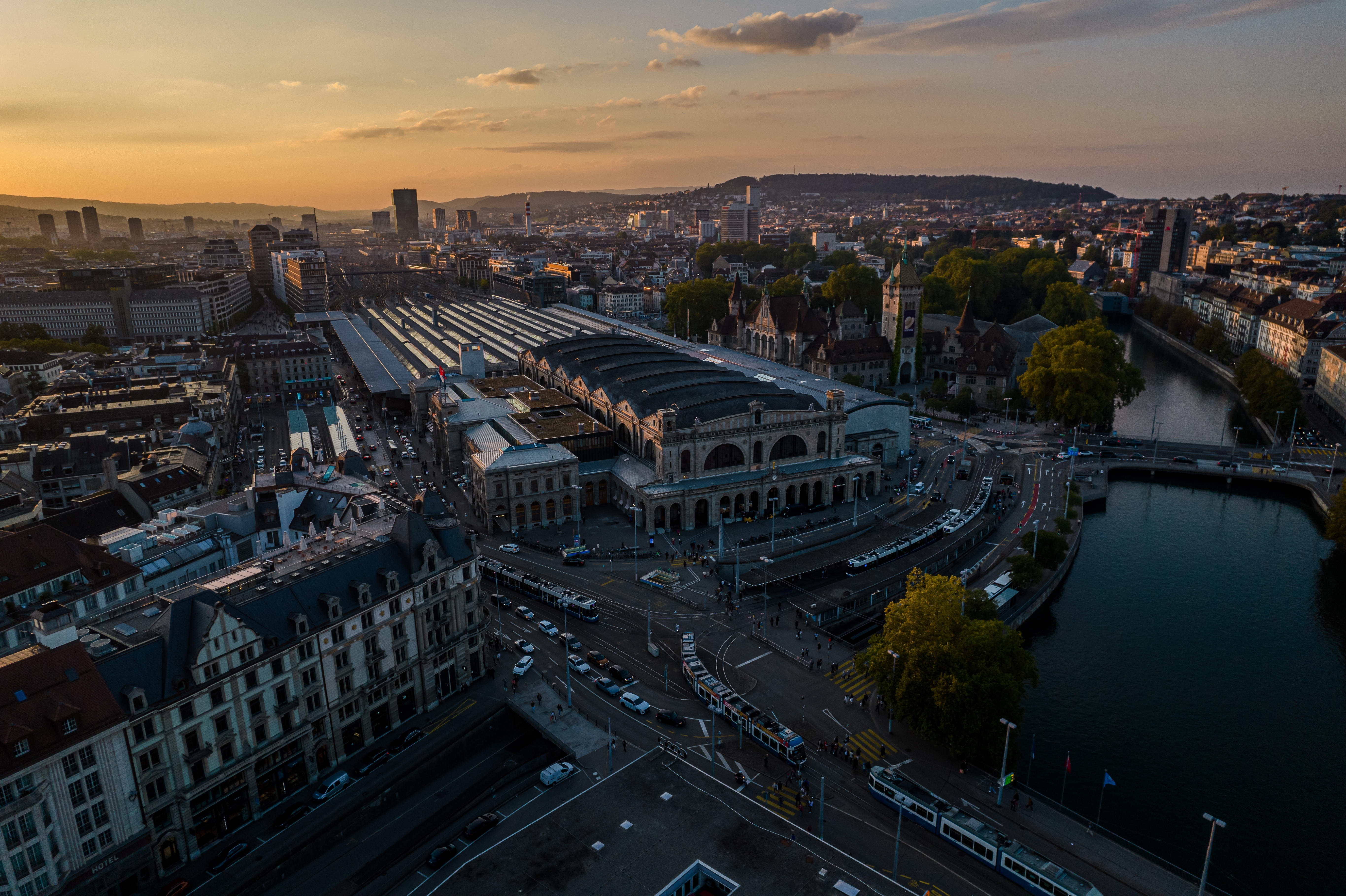 Luftfoto af Zürichs togstation og bylandskab med Limmat-floden og schweizisk arkitektur ved solnedgang