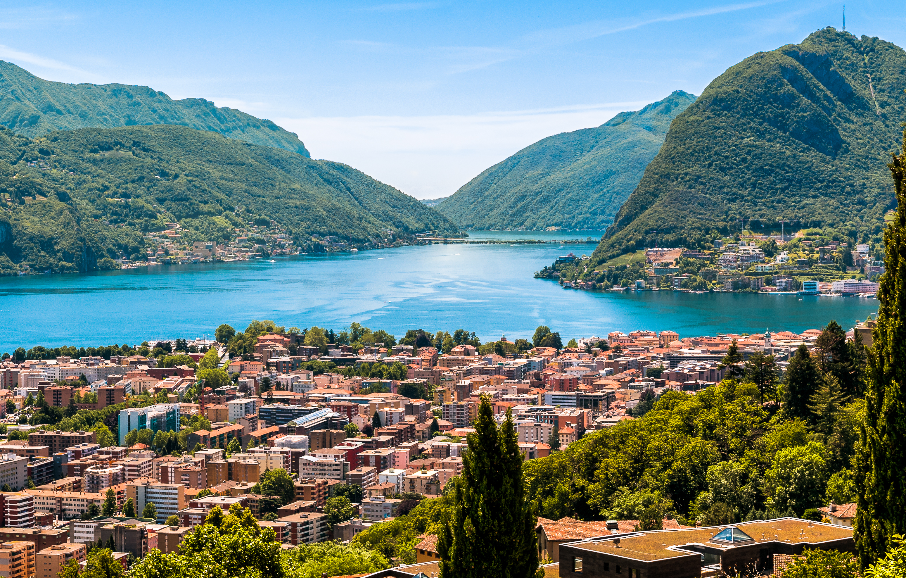 Idyllisk panorama af Lugano by ved søen med majestætiske alper i Schweiz