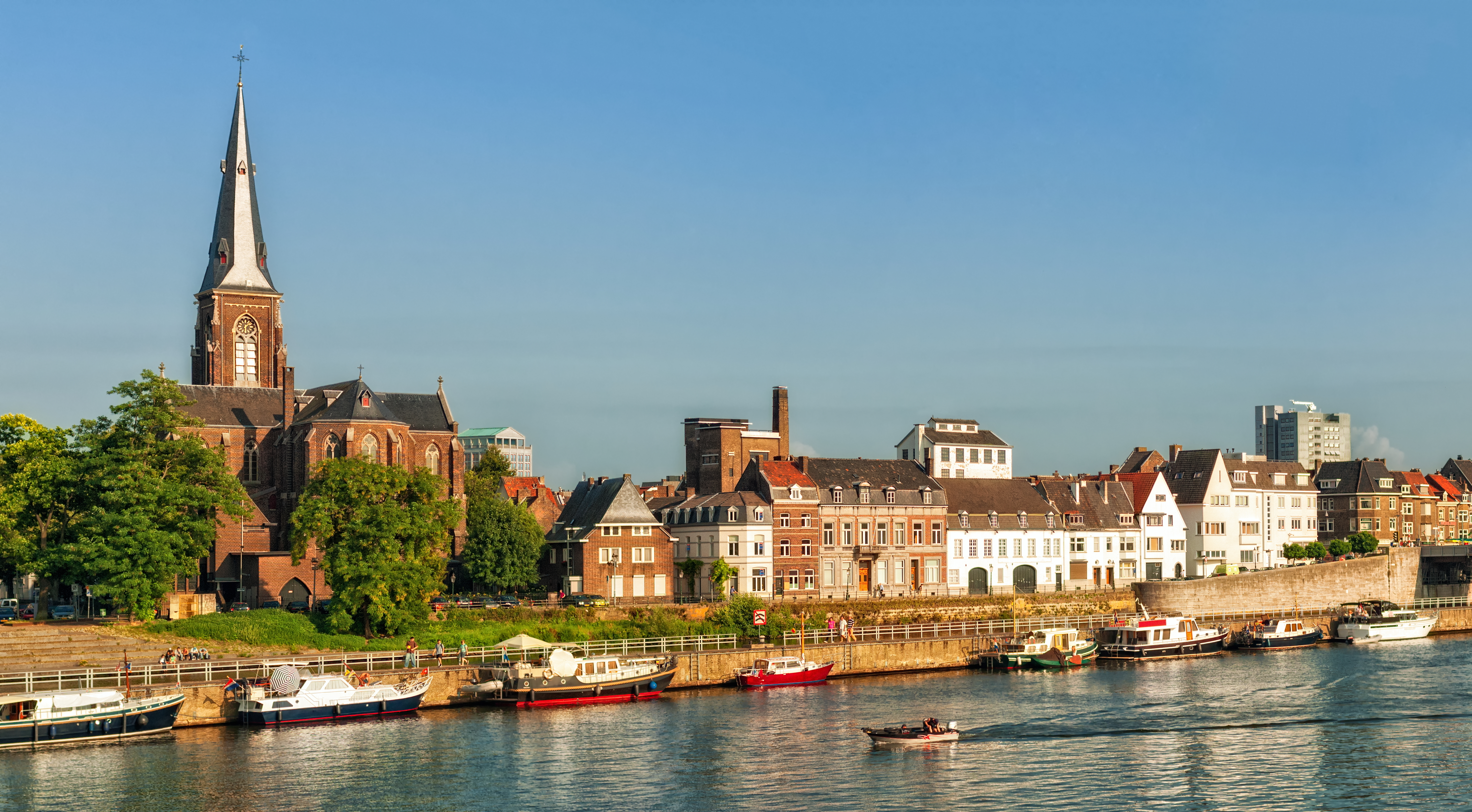 Smuk flodfront i Maastricht med gamle europæiske bygninger og kirketårn