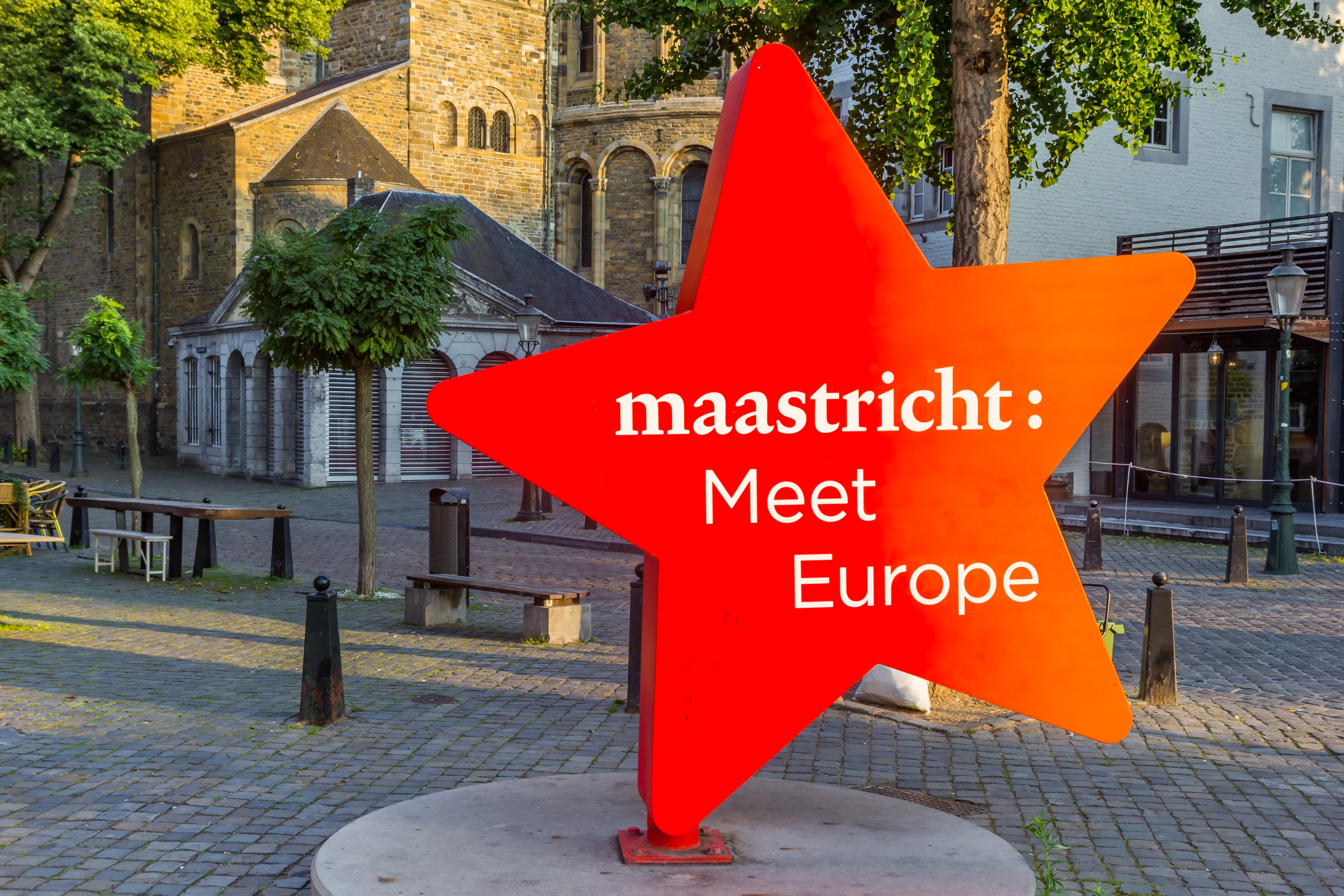 Rød og orange stjerne-skulptur med Maastricht Meet Europe på historisk torv omgivet af middelalderlige bygninger i Holland