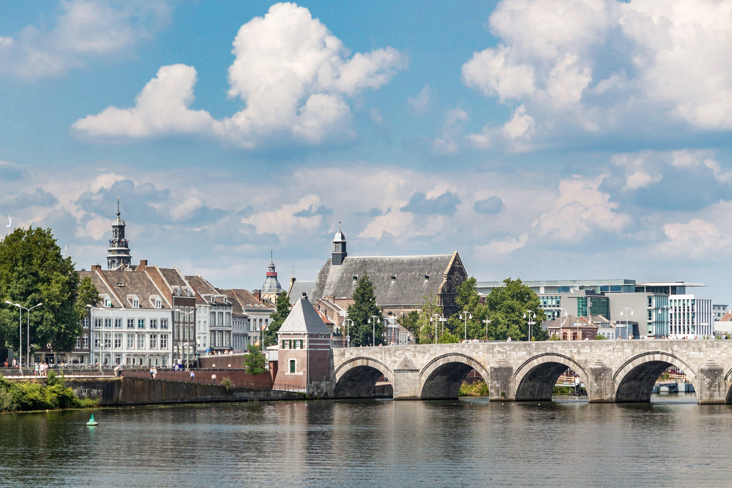 Stenbroen over floden med traditionelle hollandske bygninger og kirketaarne i Maastricht