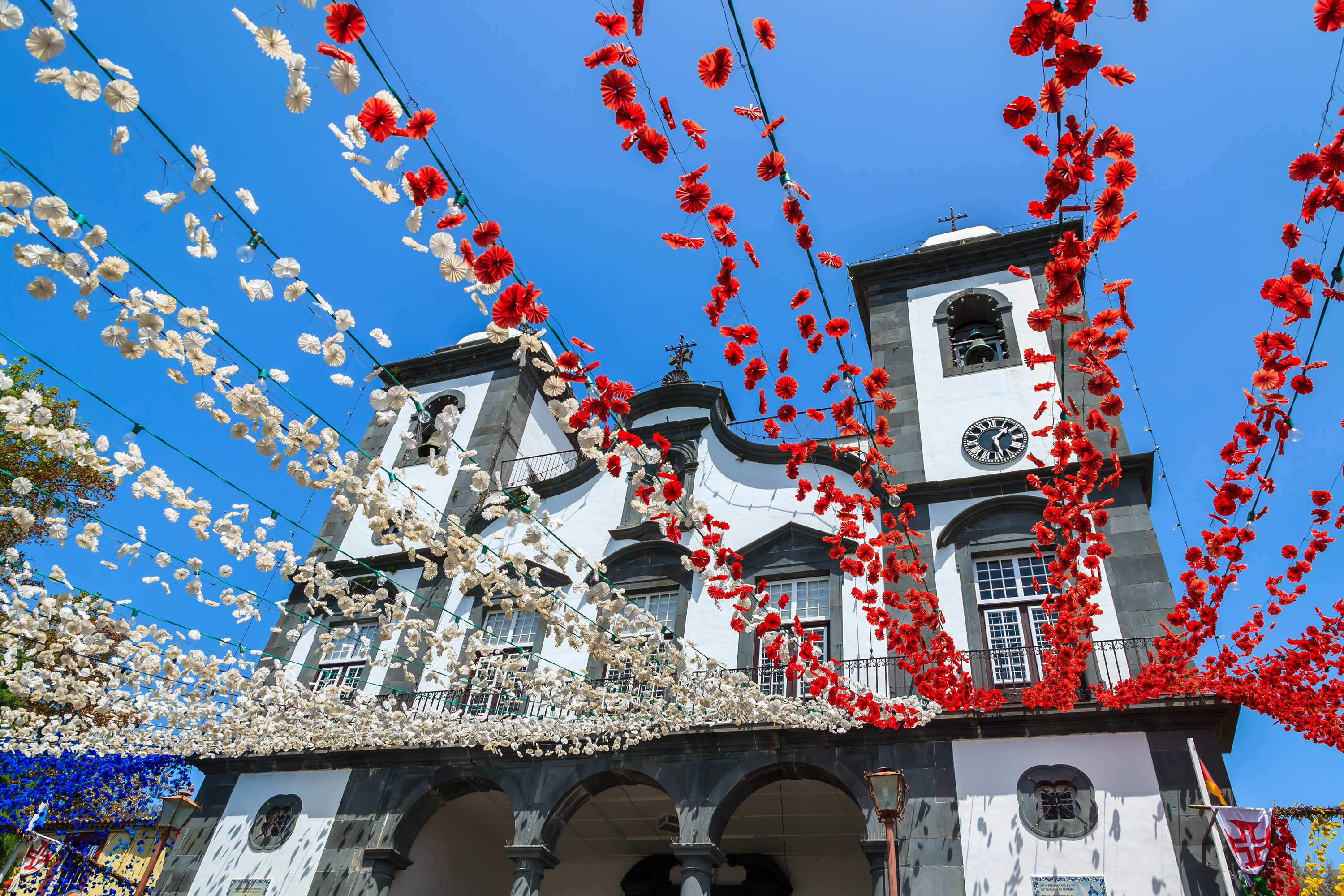Flot dekoreret kirke i Funchal på Madeira med hængende røde og hvide blomster under en festlig begivenhed