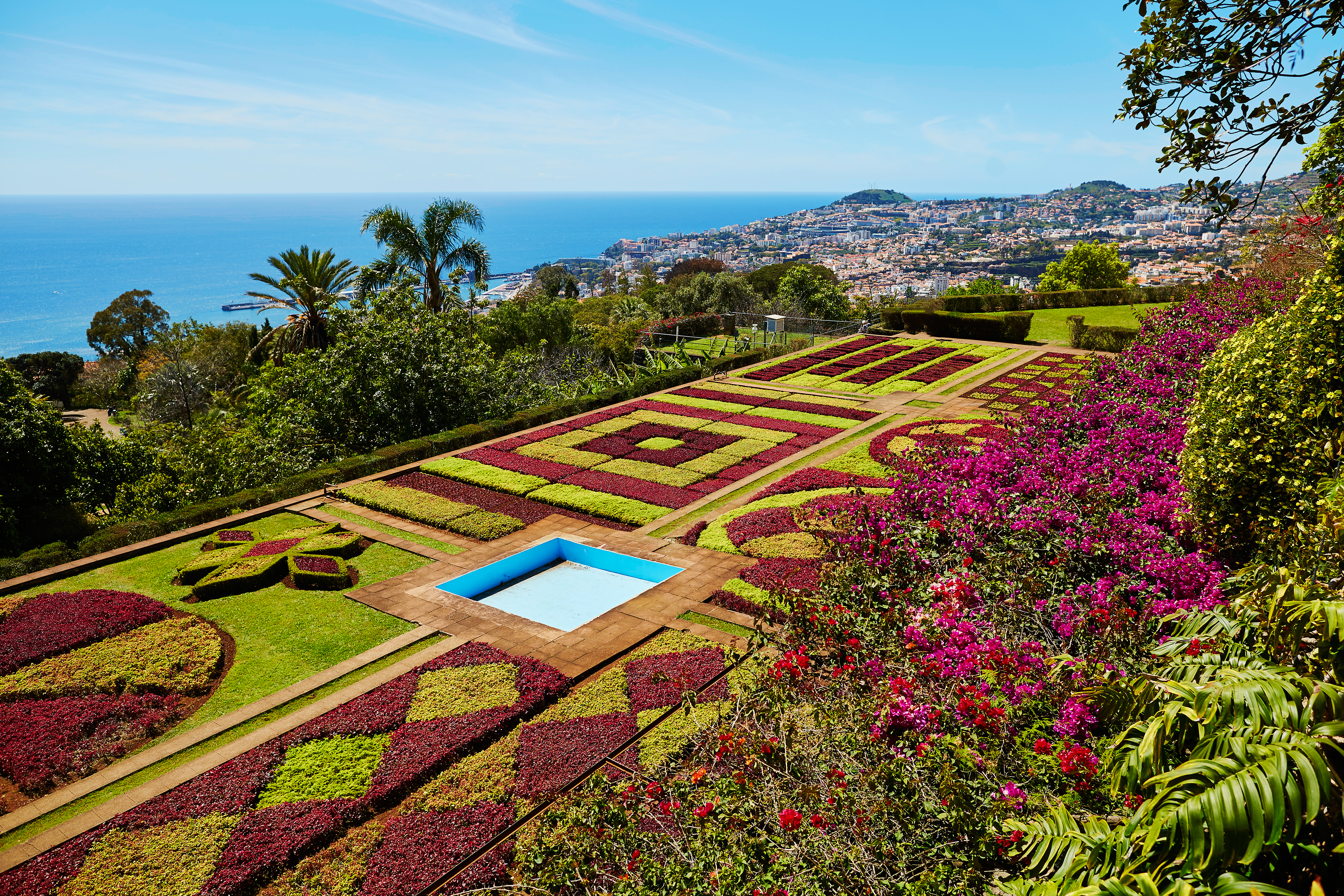 Frodige blomsterhaver med geometriske mønstre i Funchal på Madeira med spektakulær udsigt over byen og Atlanterhavet