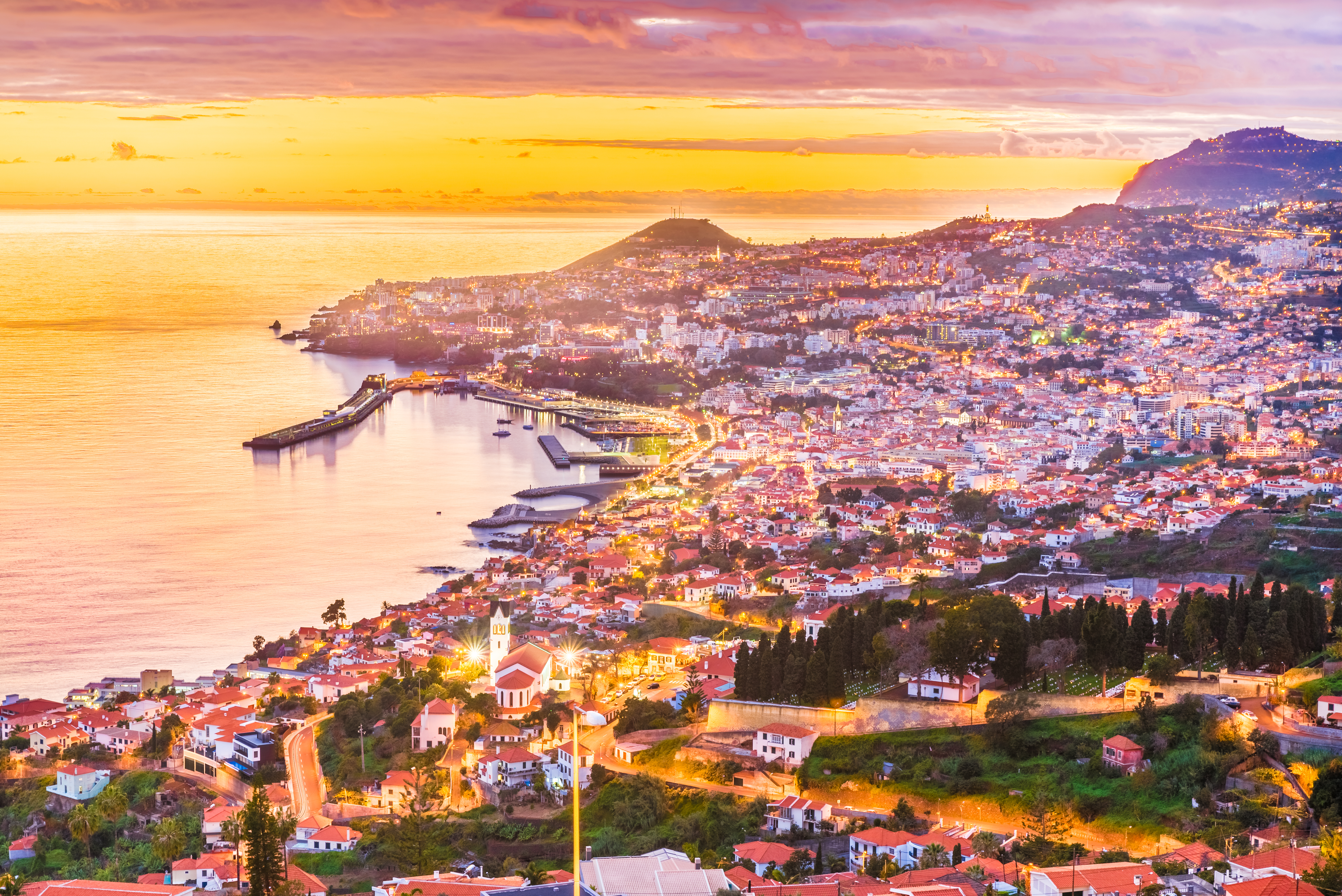 Panoramaudsigt over Funchal by på Madeira øen med solnedgang og gyldent lys over kystlinjen