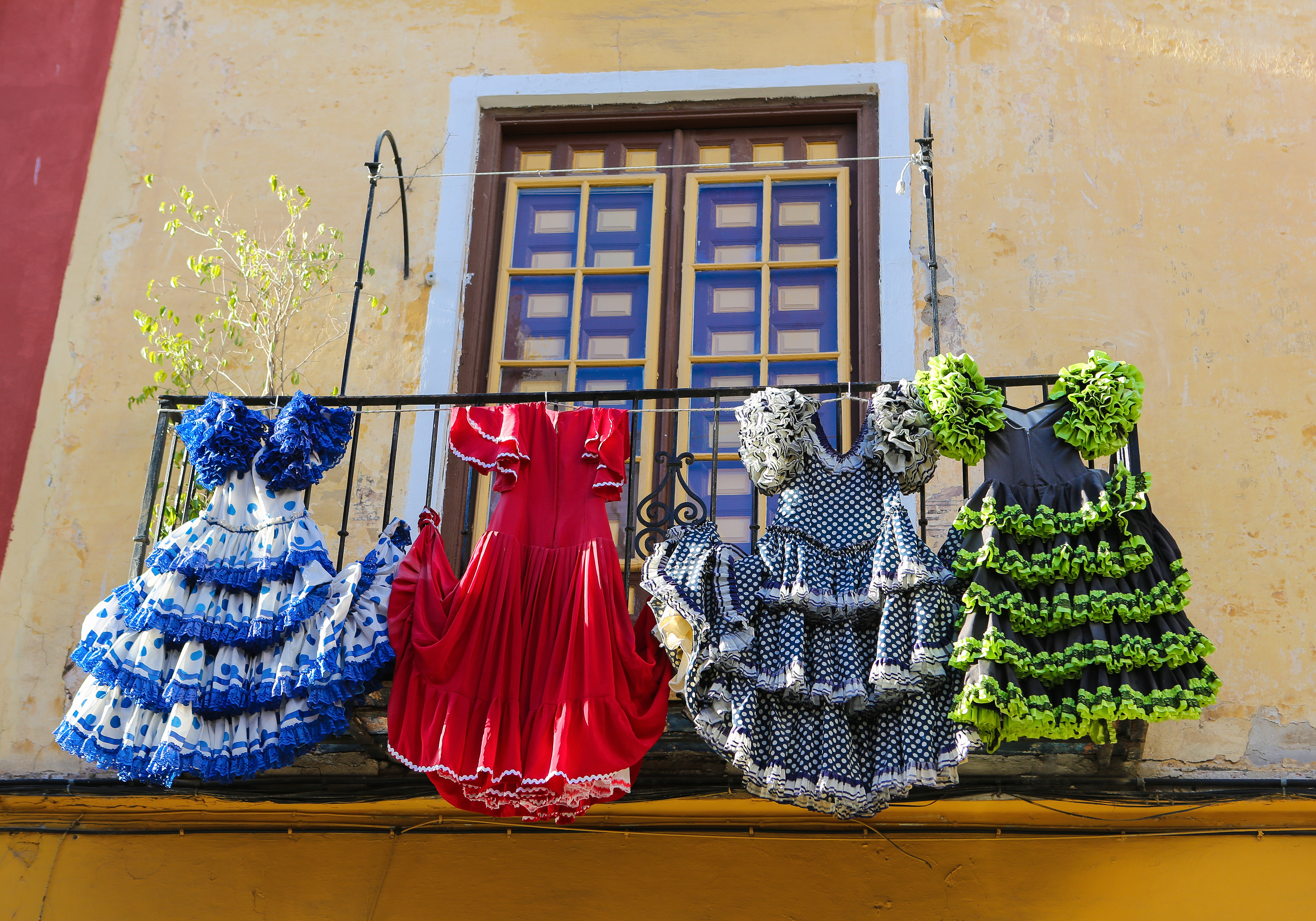 Traditionelle flamenco-kjoler i stærke farver ved et lokalt hus i Malaga, en visuel påmindelse om Andalusiens rige danse- og kulturhistorie