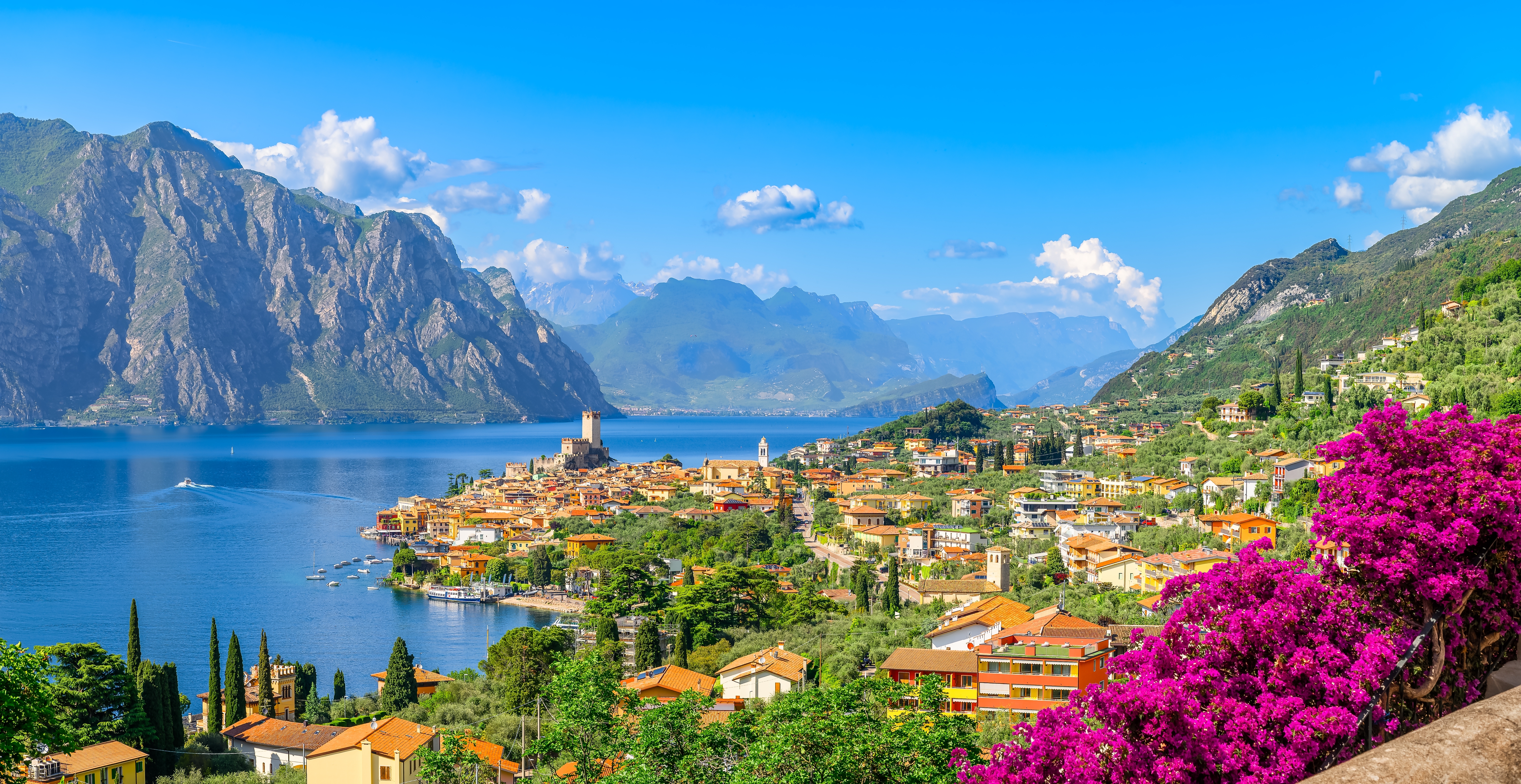 Idyllisk billede af Malcesine turistby ved Gardasøen med bjerge og farvestrålende blomster