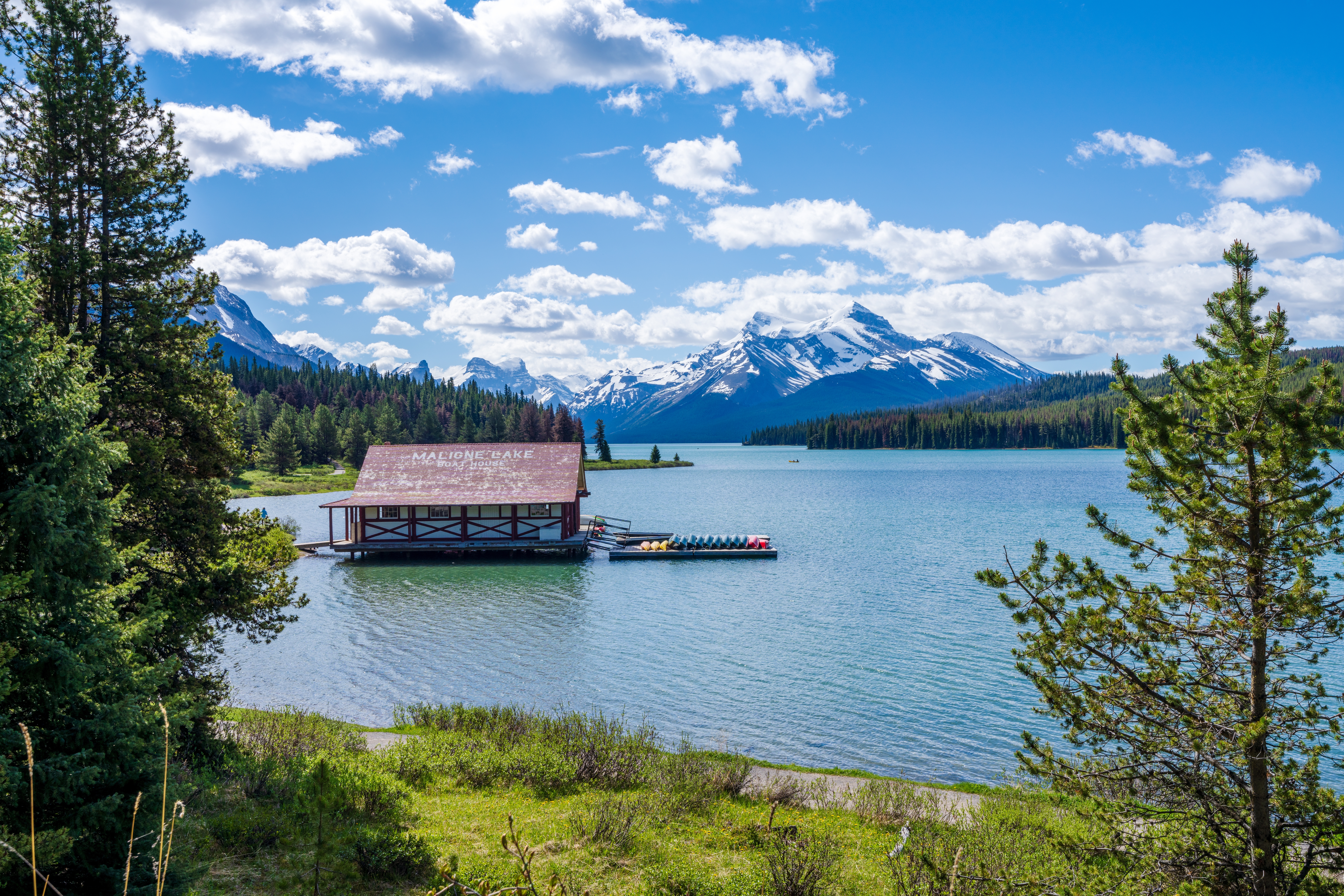Historisk bådehus ved Maligne Lake med turkisblåt vand og imponerende snedækkede Rocky Mountains, Jasper Nationalpark, Canada
