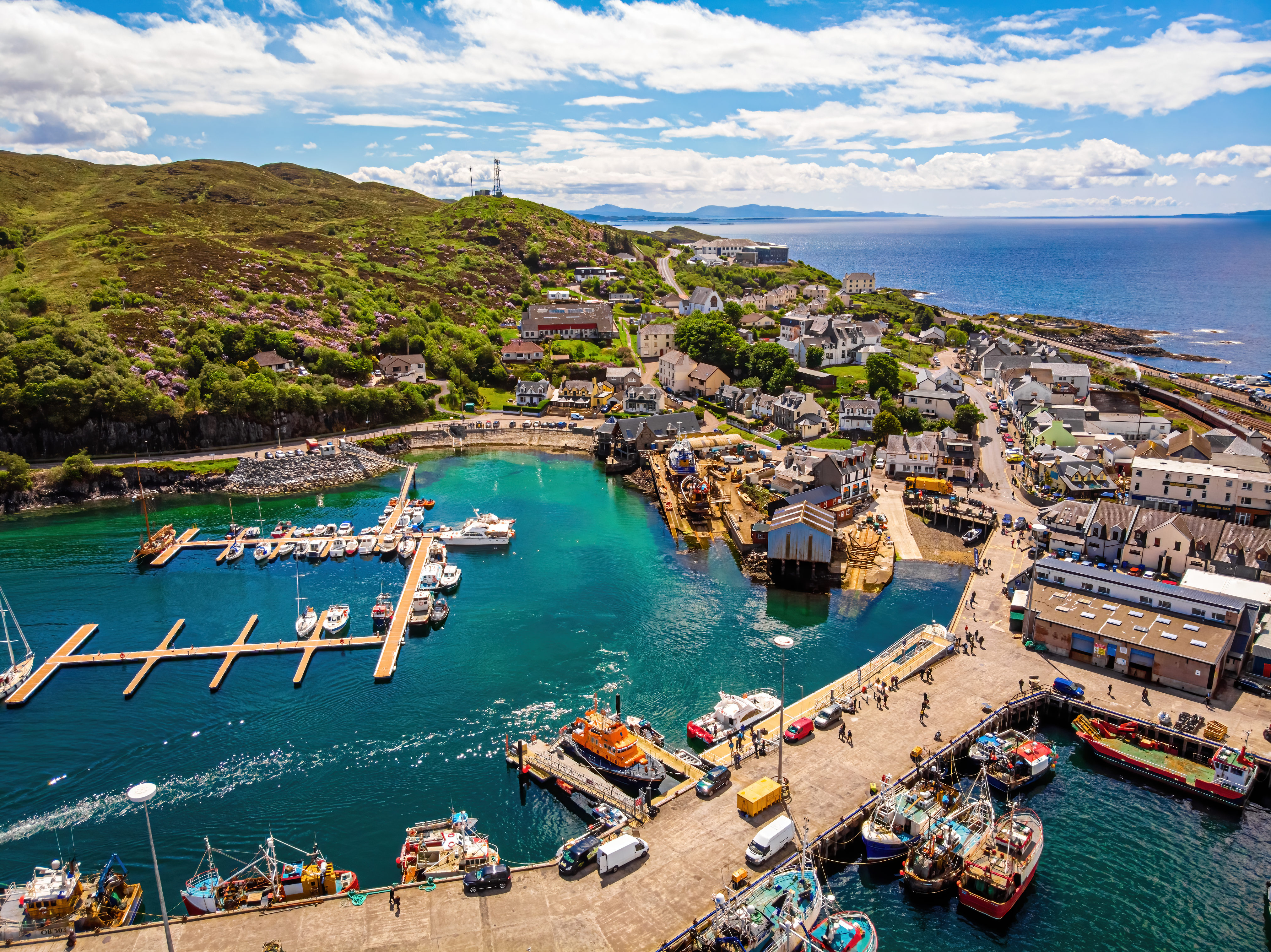 Luftfoto af den maleriske havn i Mallaig, Skotland, med fiskerbåde, marina og smuk kystby ved de skotske højlanders vestkyst