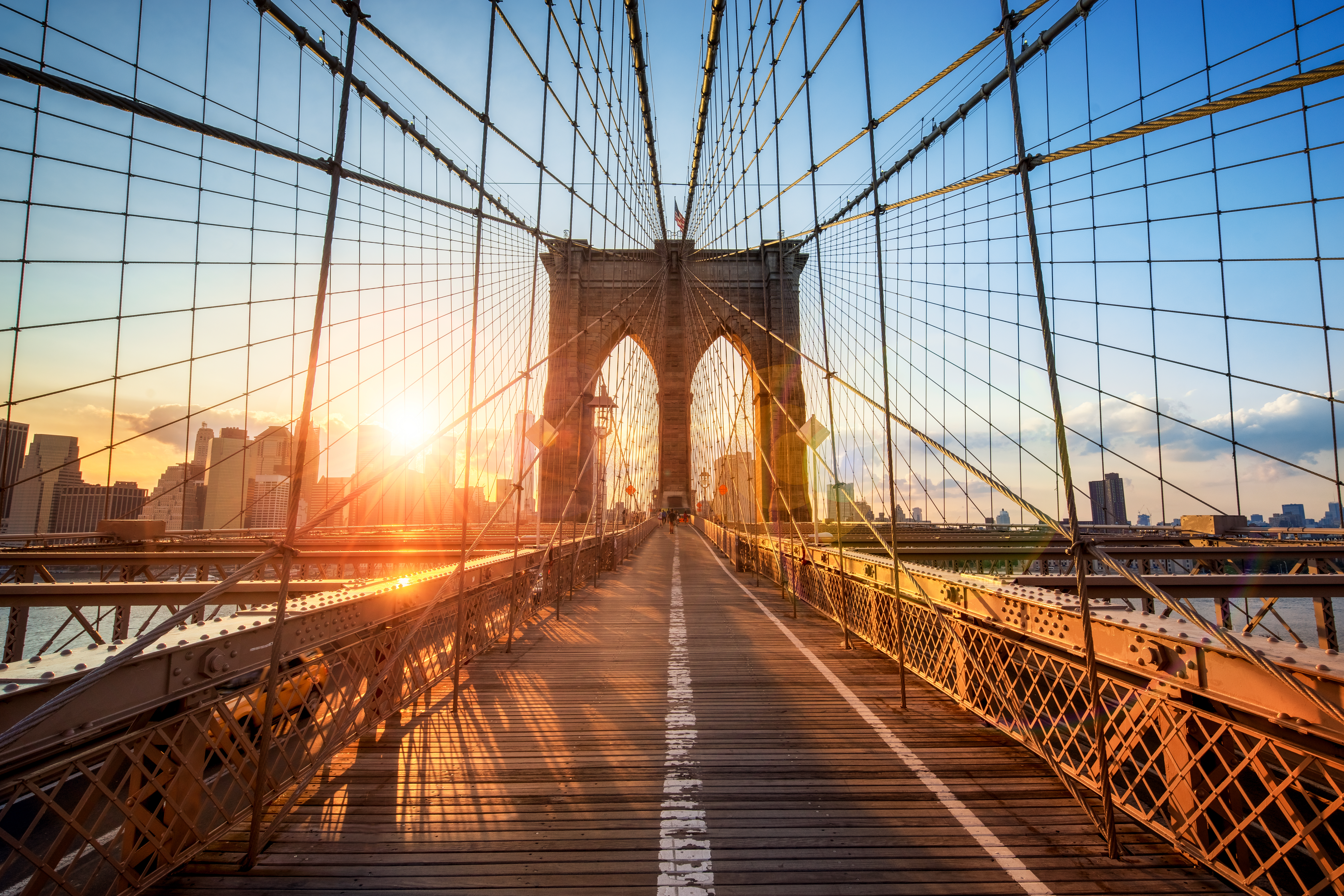 Manhattan skyline set fra Brooklyn Bridge ved solopgang i New York