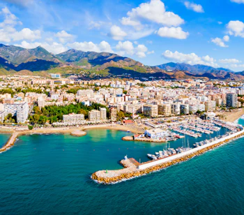 Smuk udsigt over Marbella marina og kystby med bjerge Costa del Sol