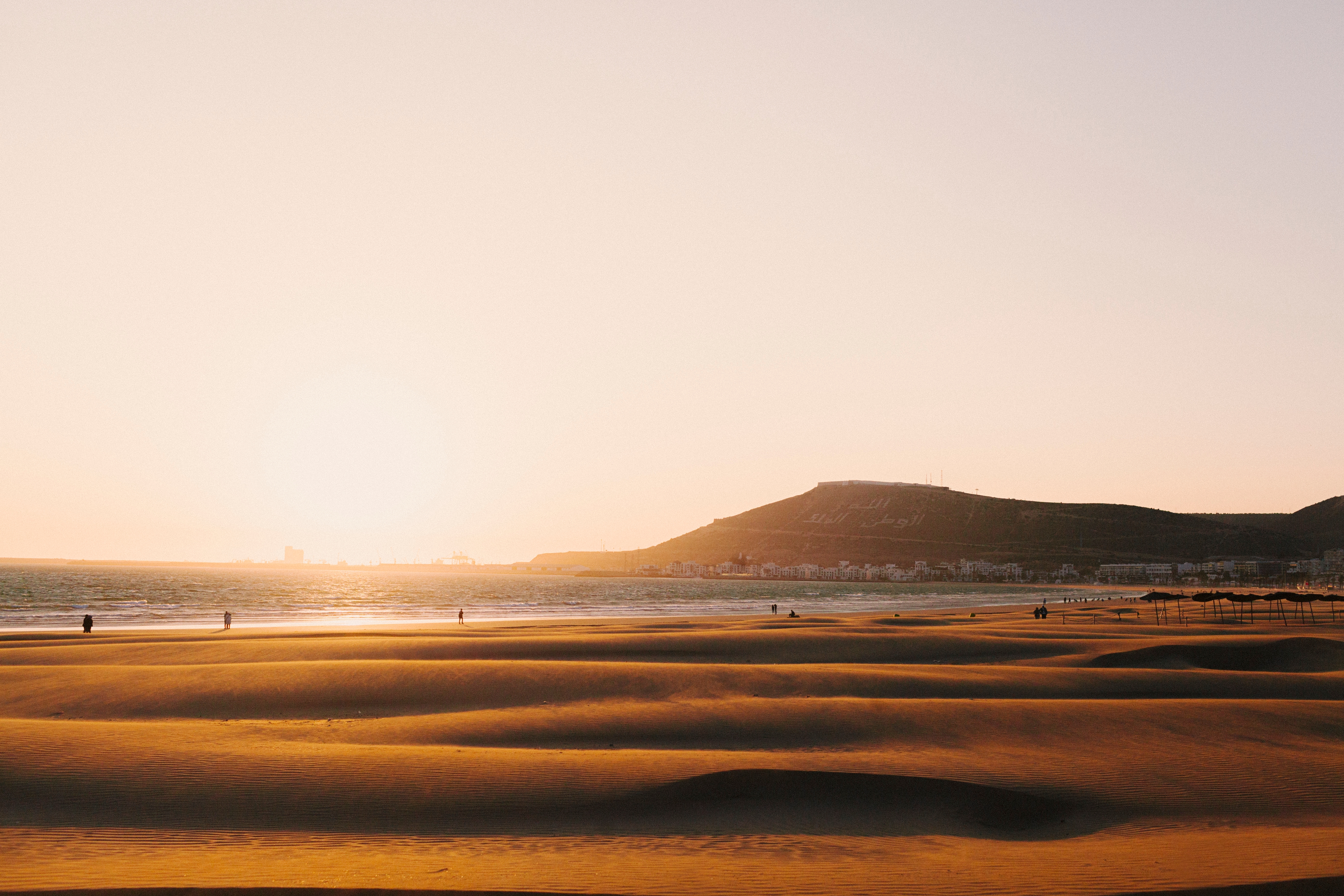 Romantisk solnedgang på Agadir strand i Marokko med gylden belysning og bjerge