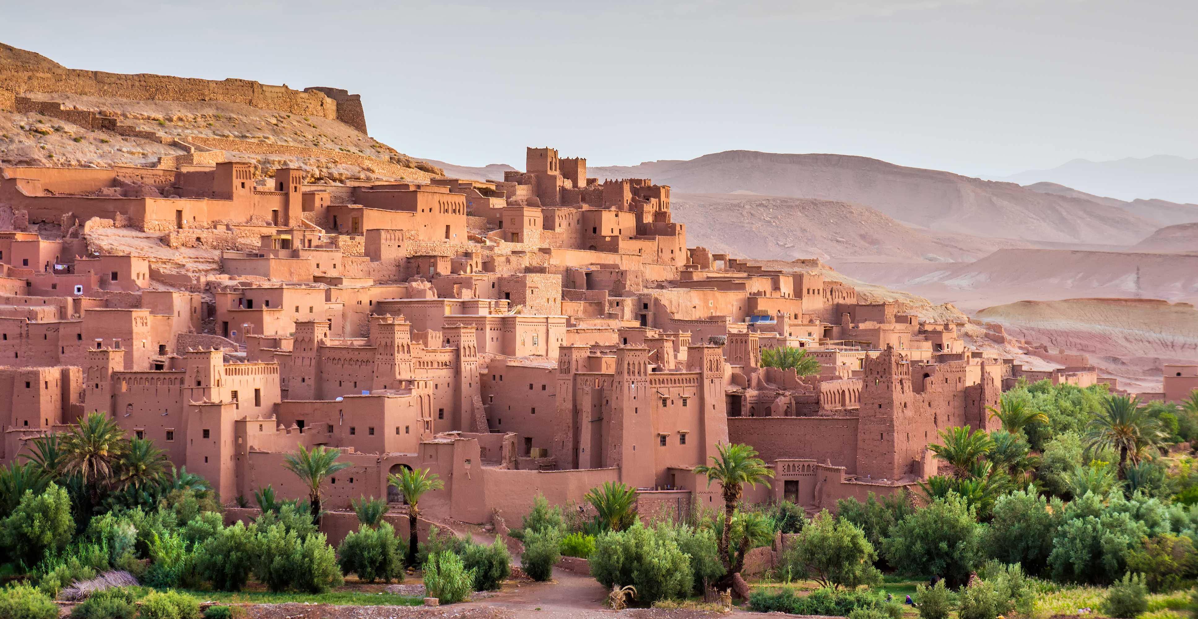 Historisk berberby Ait Ben Haddou med middelalderlige lerfæstninger og tårne omgivet af frodig vegetation ved Atlas-bjergene i Marokko