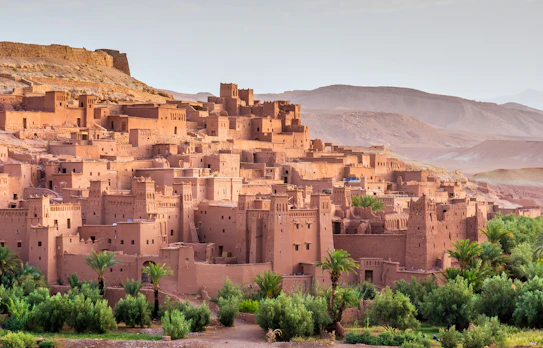 Historisk berberby Ait Ben Haddou med middelalderlige lerfæstninger og tårne omgivet af frodig vegetation ved Atlas-bjergene i Marokko