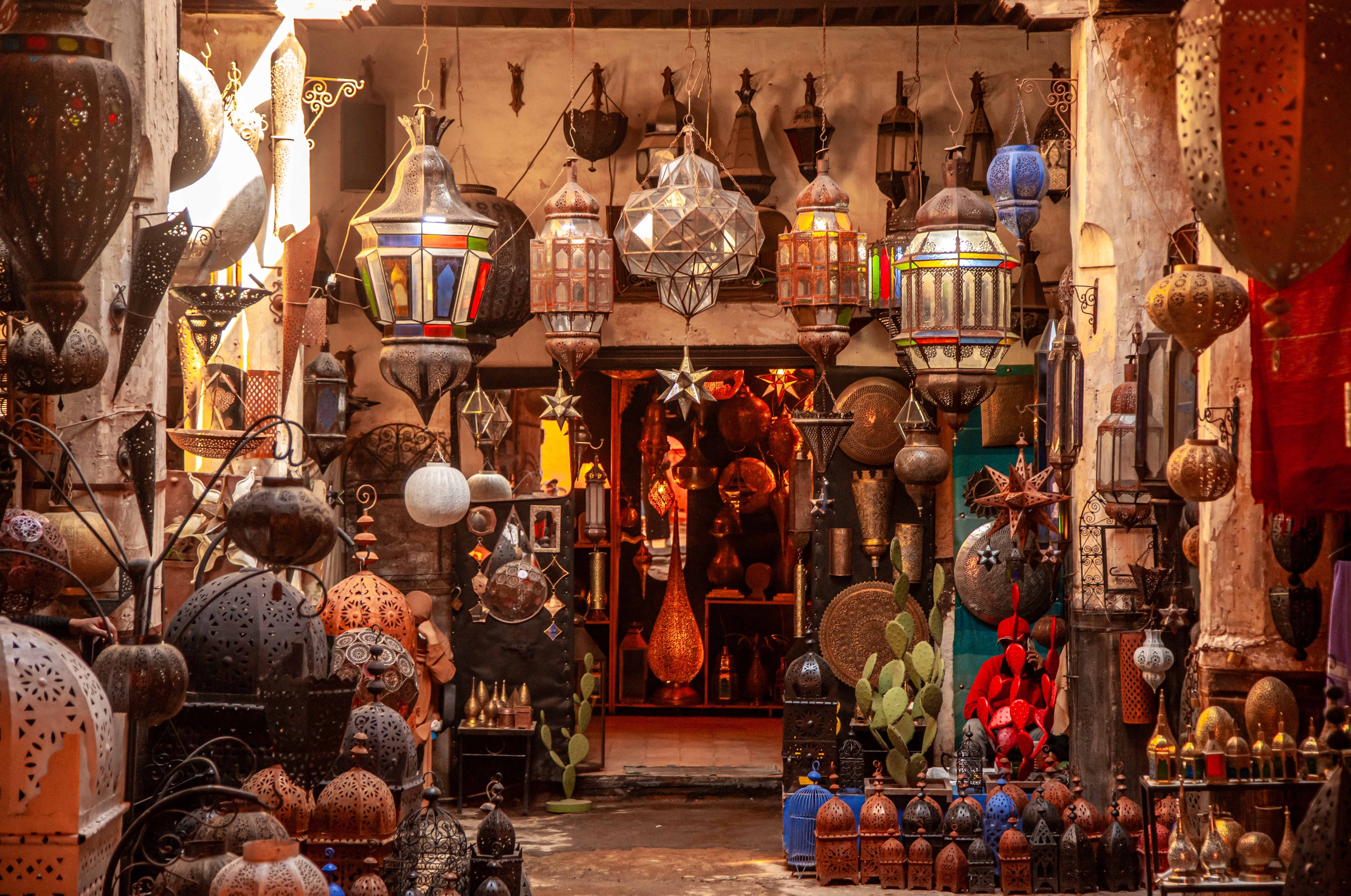 Fascinerende syn af traditionelle marokkanske lamper med ornamenterede mønstre og farverige glaspaneler, der hænger i en karakteristisk butik i den stemningsfulde souk-markedsplads i Marrakech