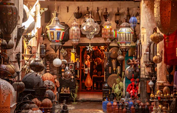 Fascinerende syn af traditionelle marokkanske lamper med ornamenterede mønstre og farverige glaspaneler, der hænger i en karakteristisk butik i den stemningsfulde souk-markedsplads i Marrakech