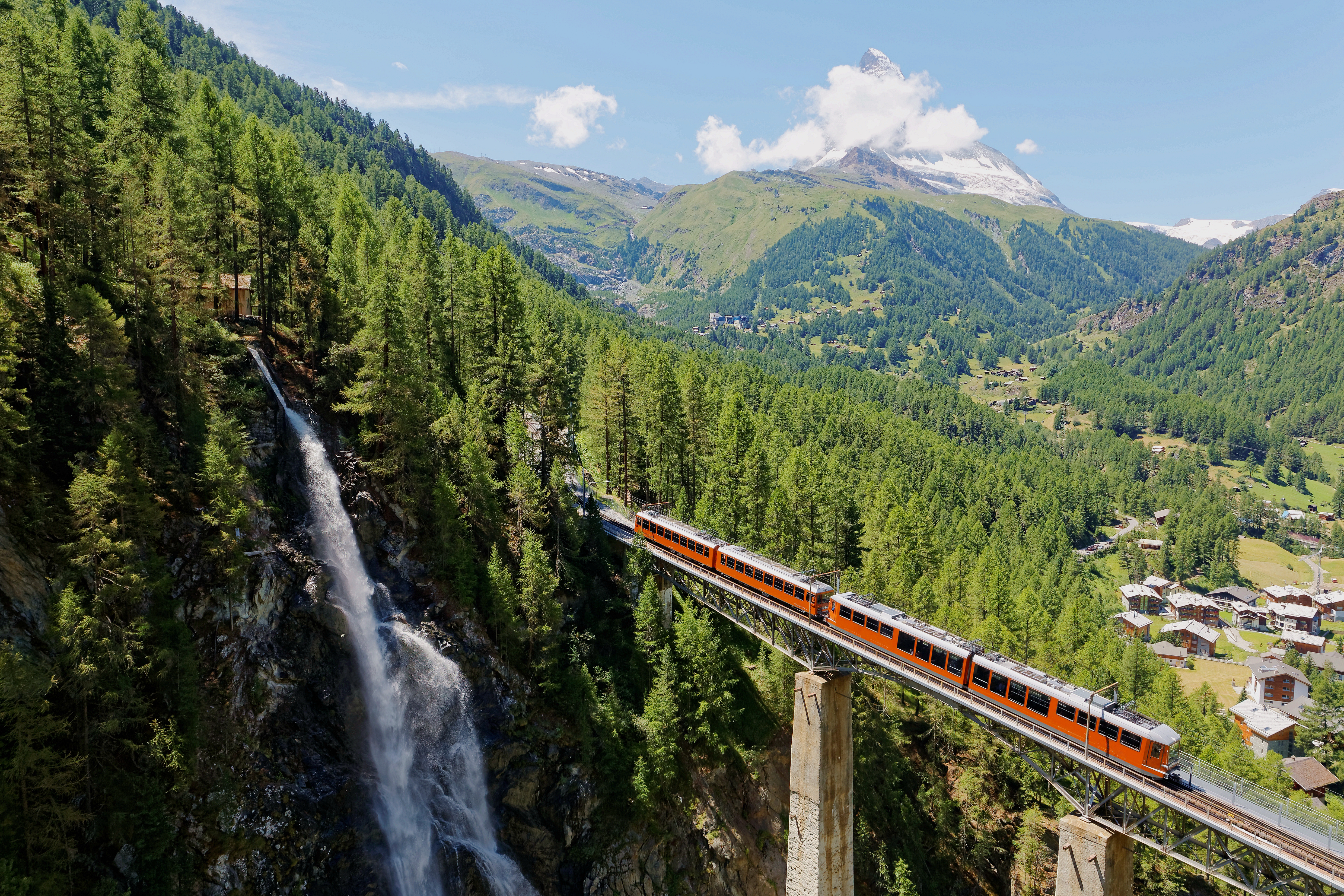 Betagende udsigt over Gornergrat-toget der krydser en viadukt over Findelbach-vandfaldet med det imponerende Matterhorn-bjerg som kulisse i de schweiziske alper
