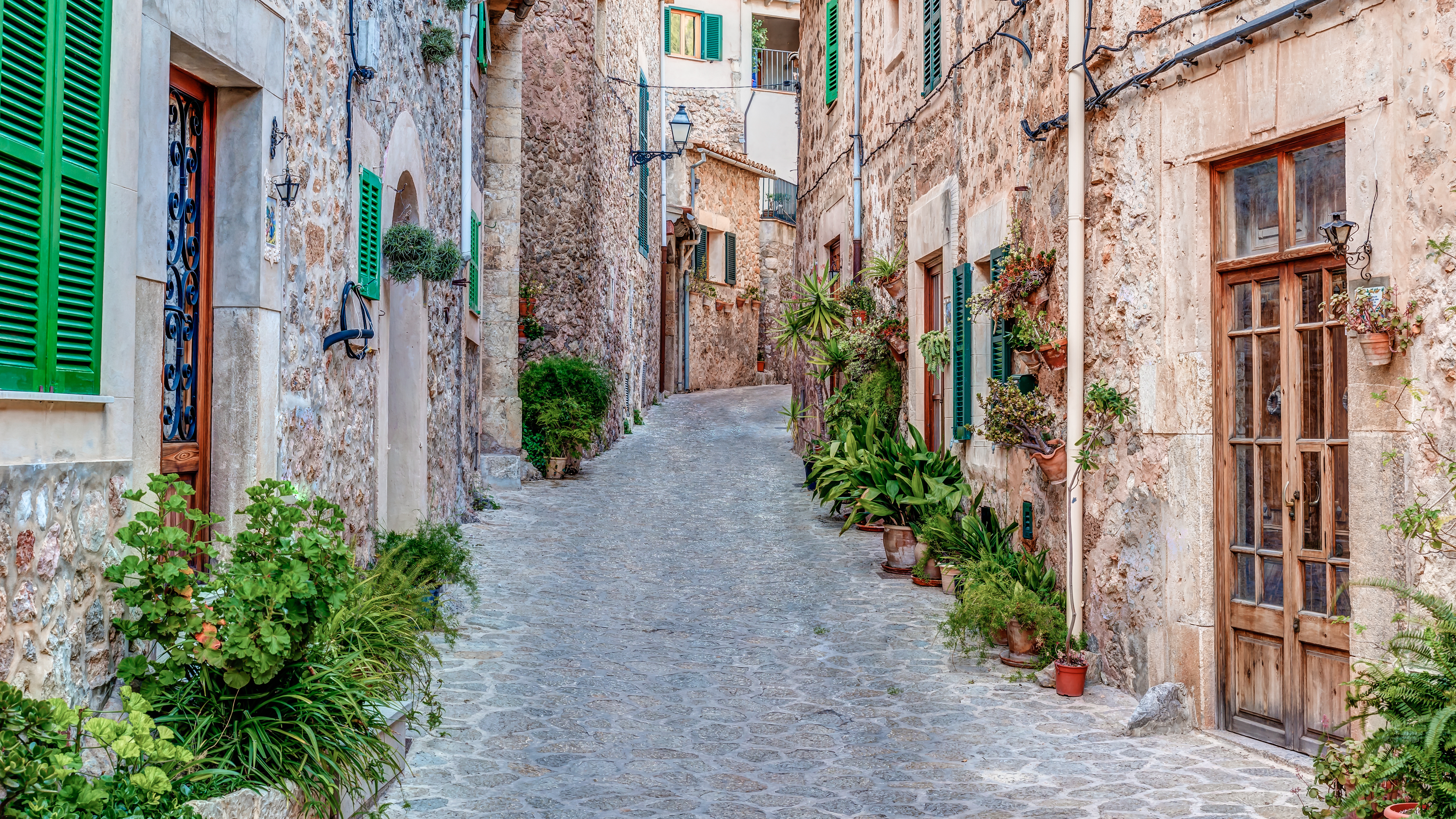 Smalle brostensbelagte gade med traditionelle mallorquinsk arkitektur i Valldemossa
