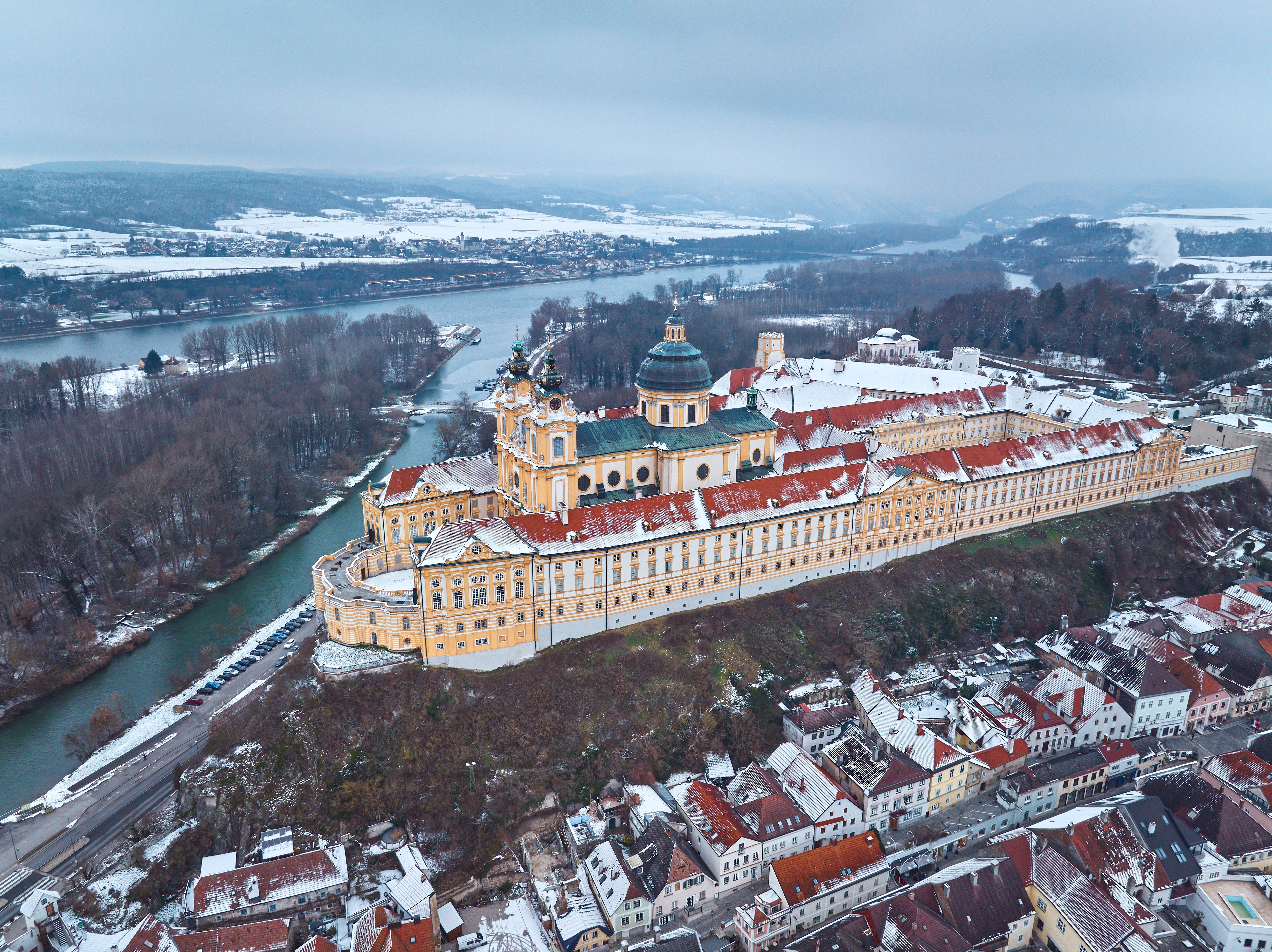 Det imponerende barokke Melk Kloster dækket af sne, fotograferet fra luften over Donau og Wachau-dalen i Østrig