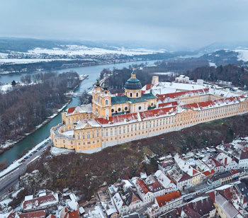 Det imponerende barokke Melk Kloster dækket af sne, fotograferet fra luften over Donau og Wachau-dalen i Østrig