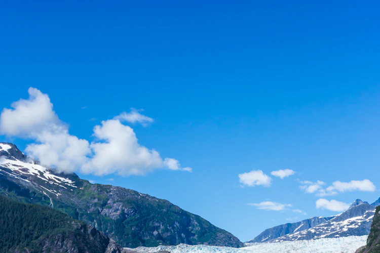 Naturskønt panorama over Mendenhall-gletsjeren og isblå gletsjersø omringet af bjerge og frodig natur i Juneau, Alaska