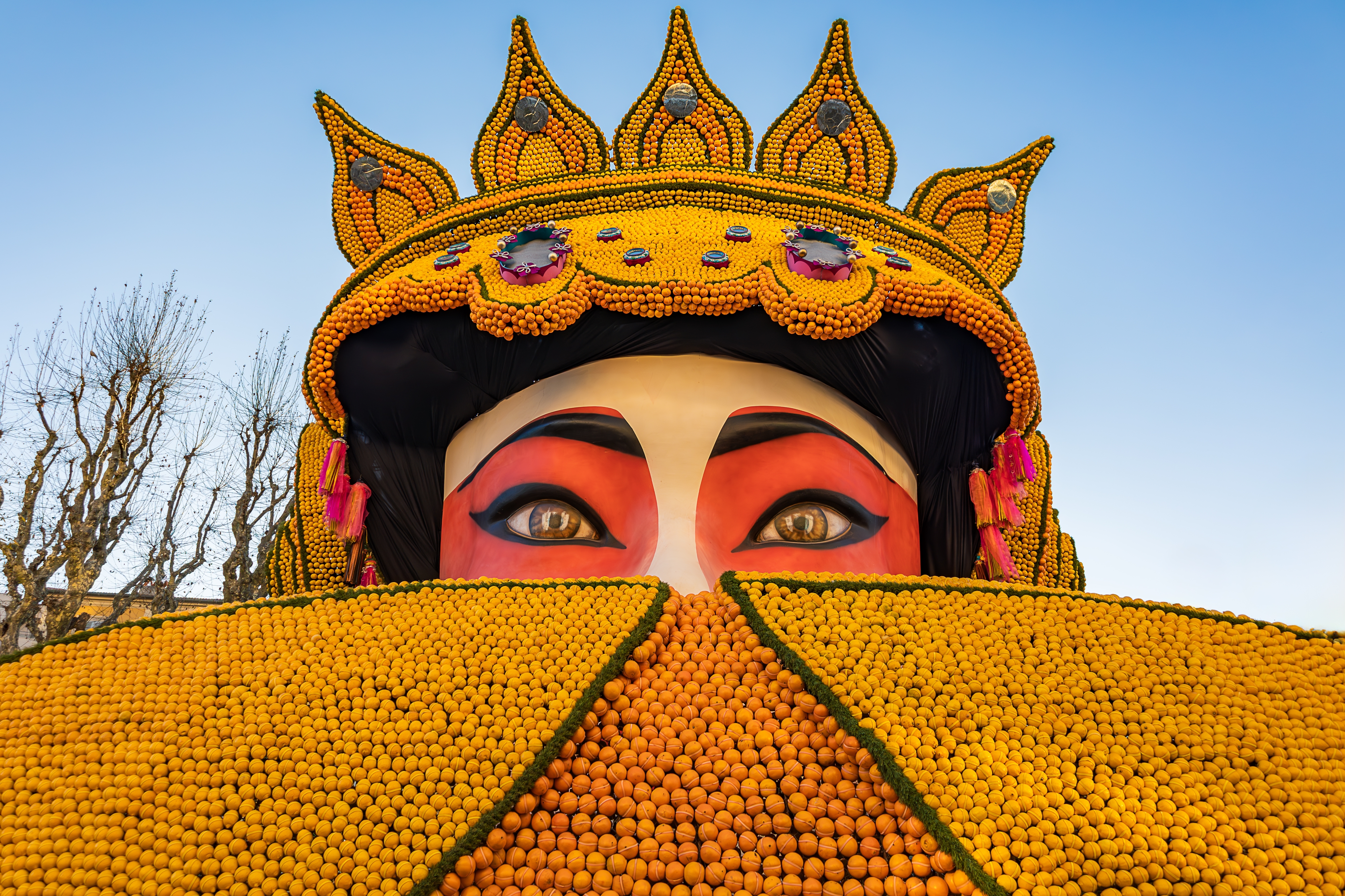 Kæmpe festlig figur af citroner og appelsiner fra Menton Citron Festivalen i Sydfrankrig med farverigt opera-ansigt og guldkrone