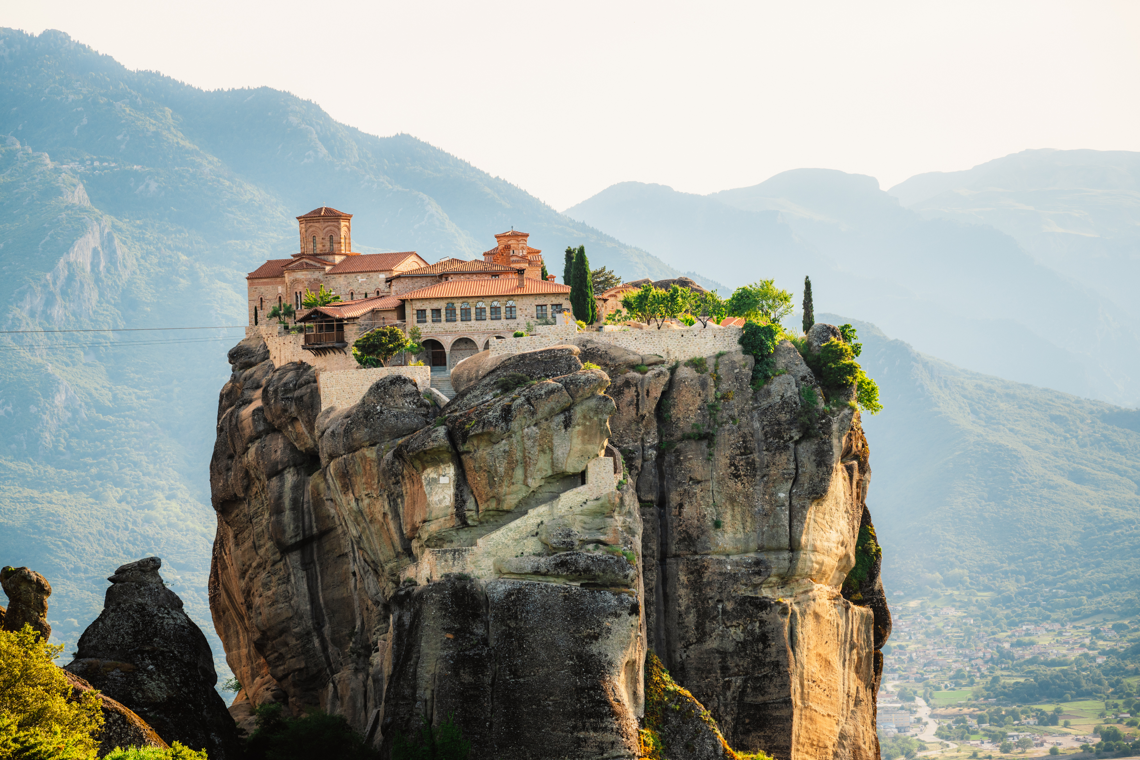 Det storslåede kloster i Meteora, Grækenland, tronende øverst på de karakteristiske klippeformationer med panoramaudsigt over det grønne bjerglandskab