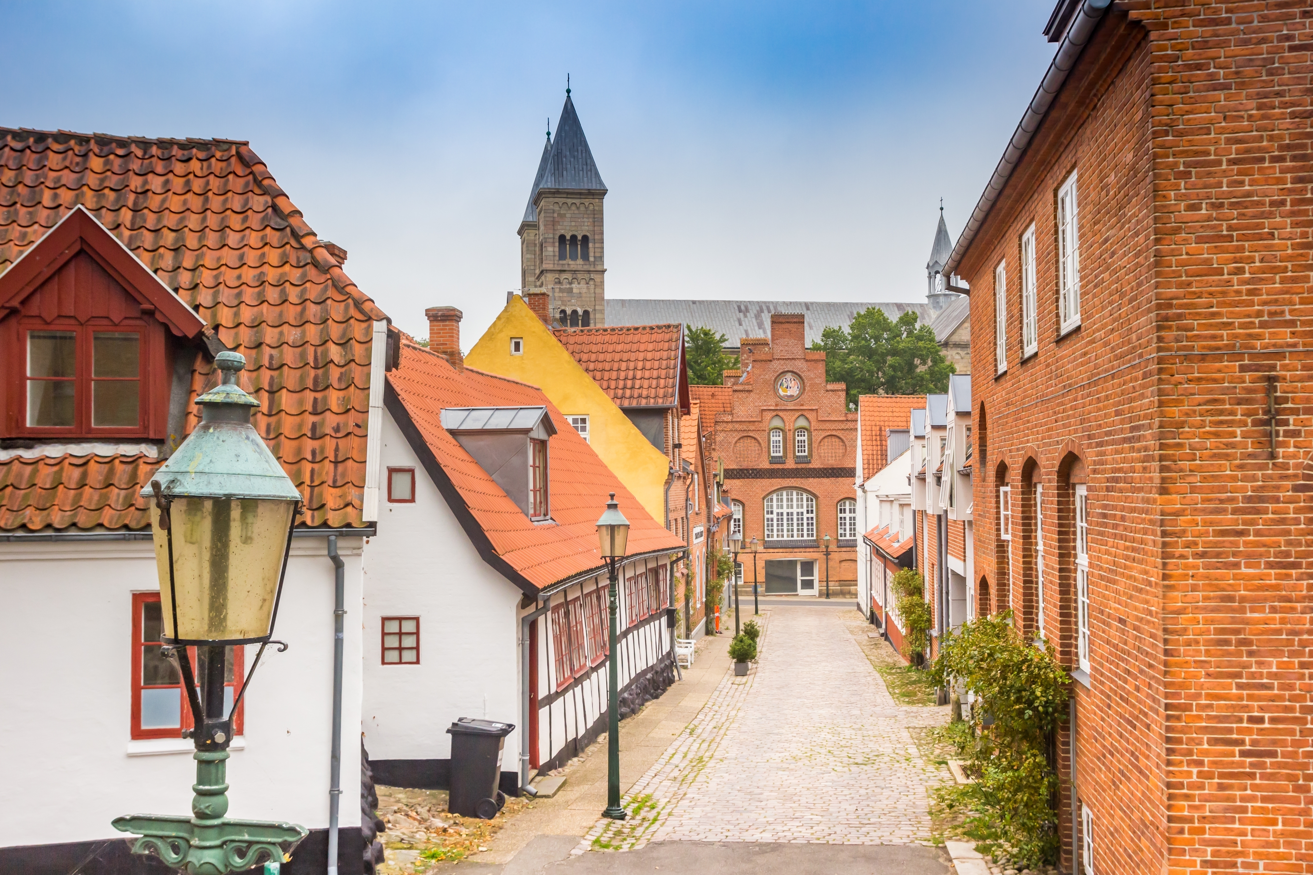 Middelalderby med teglhuse, kirketårn og brolagte gade i skandinavisk stil