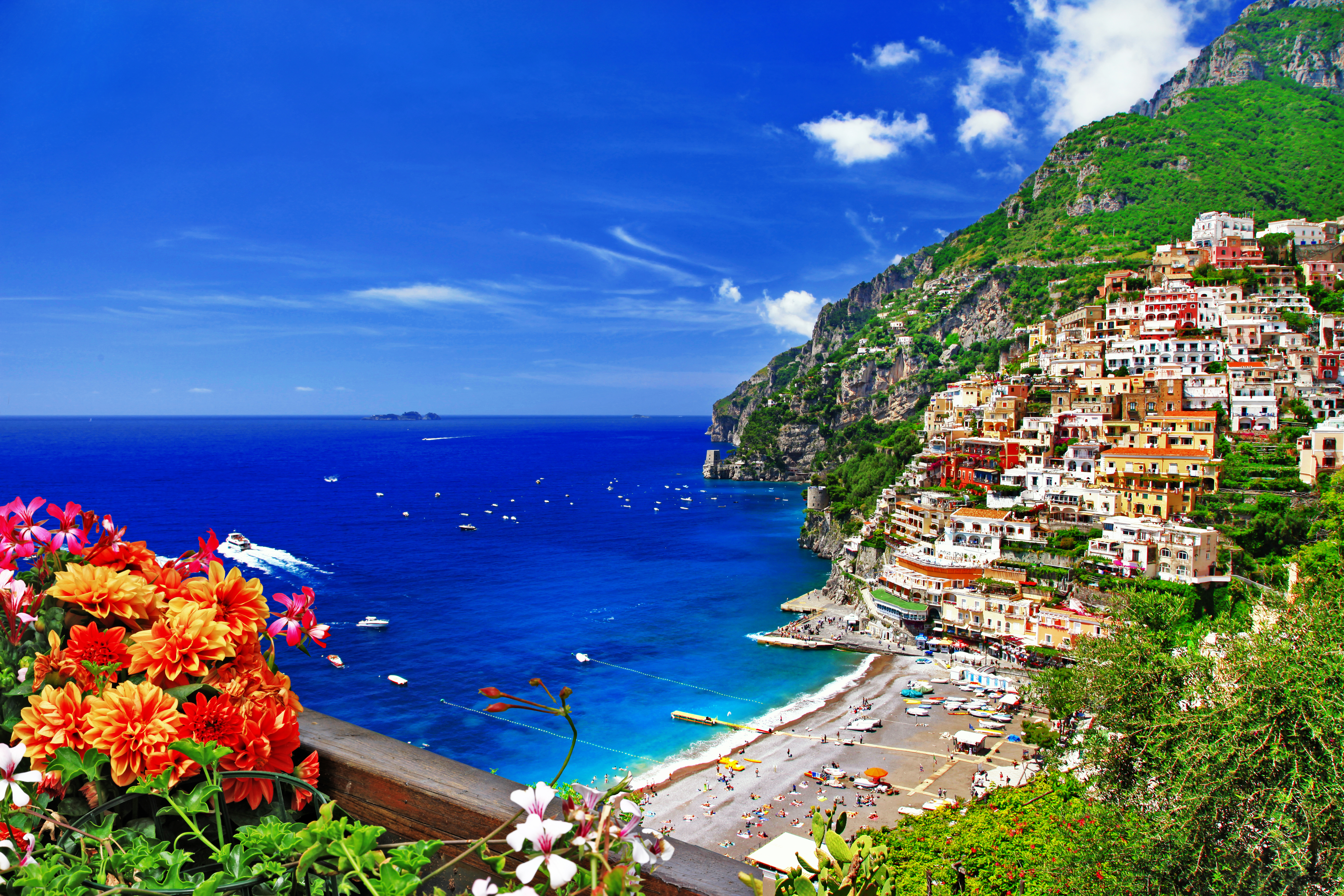 Spektakulær udsigt over Positano landsby på Amalfi-kysten med blomster i forgrunden og blåt middelhav