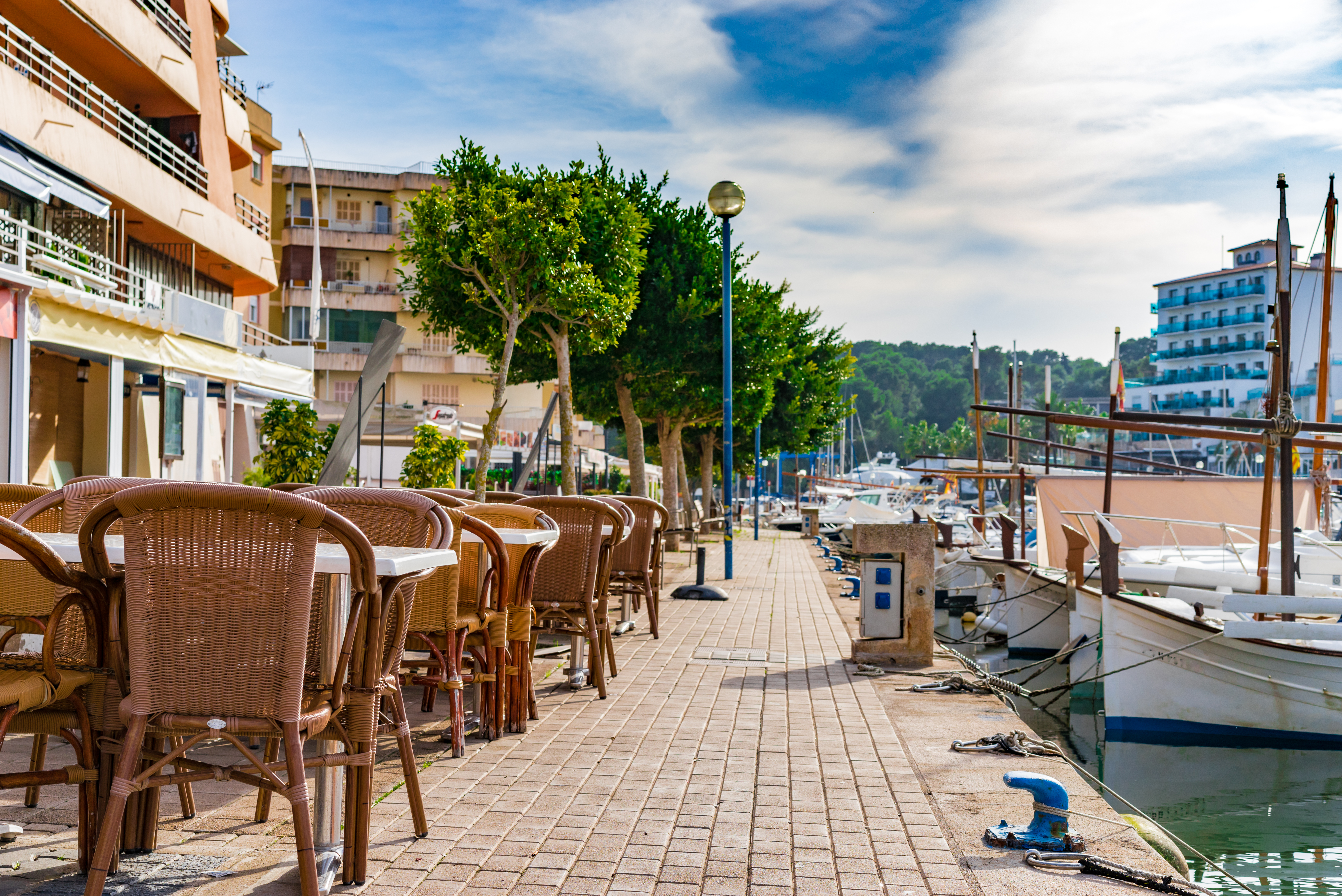 Solrig havnepromenade med restaurantterrasse og marinaomraade i Mallorca