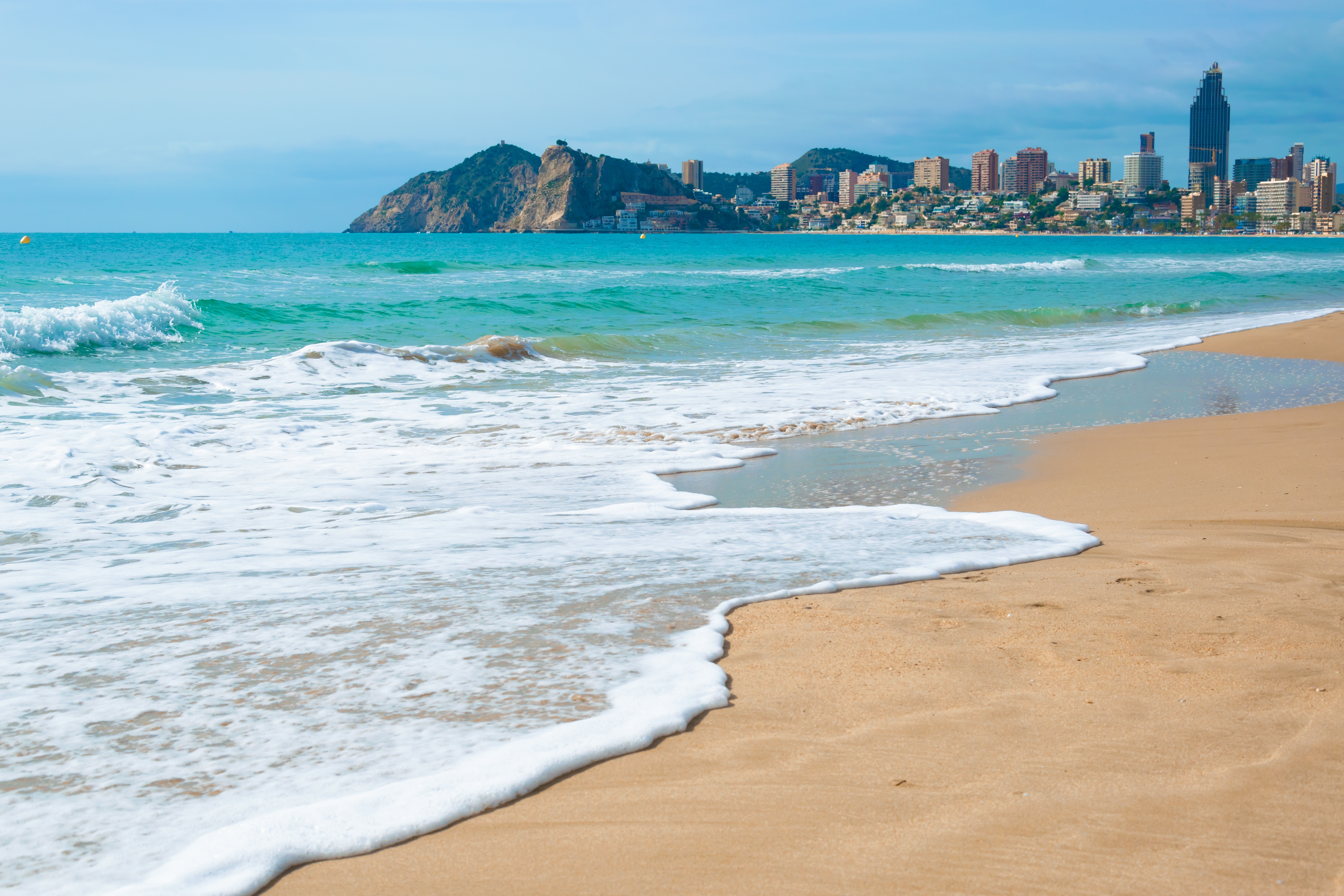 Idyllisk Benidorm strand med klart middelhavsvand og moderne bygninger, Costa Blanca