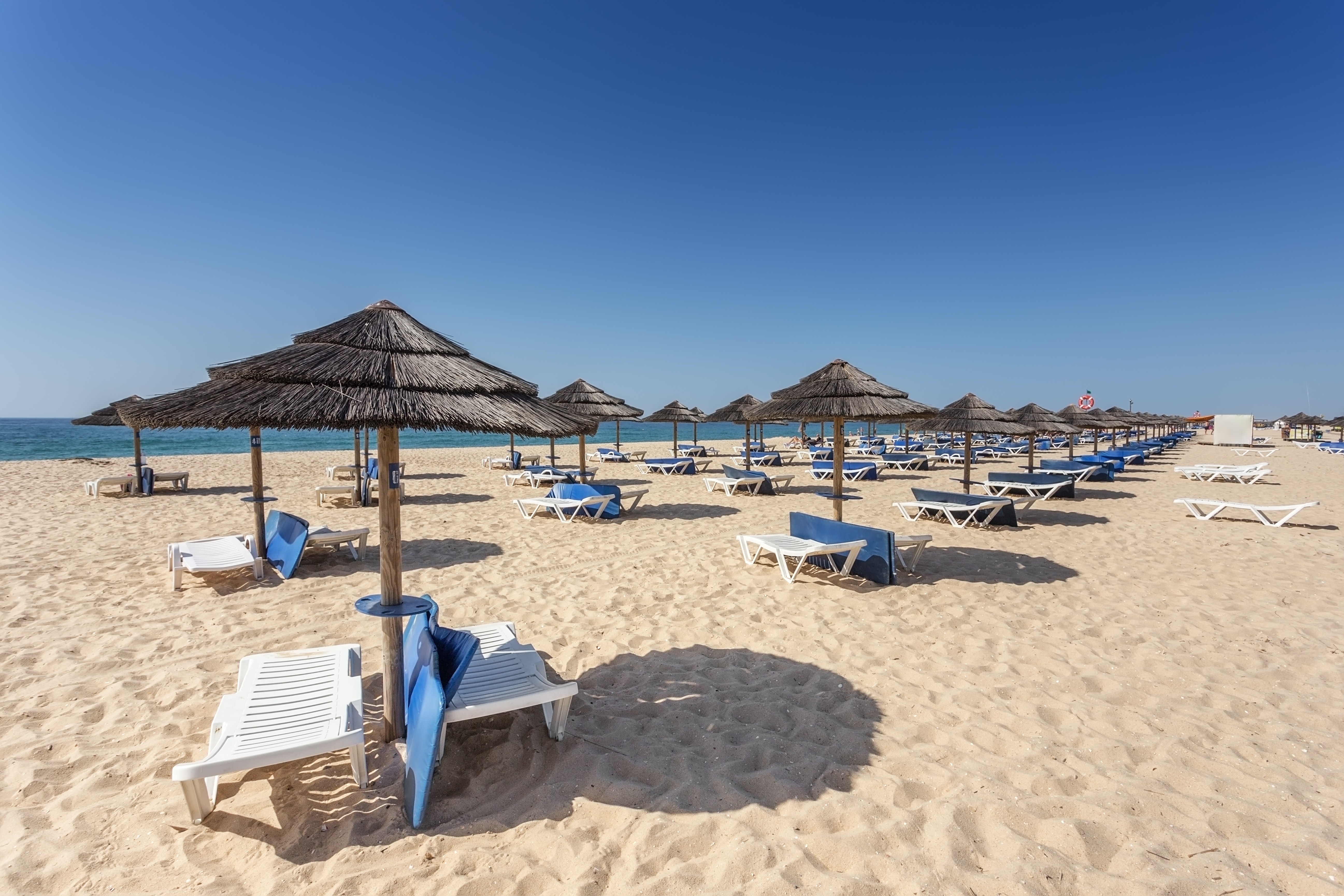 Middelhavsstrand med solsenge og parasol i Portugal