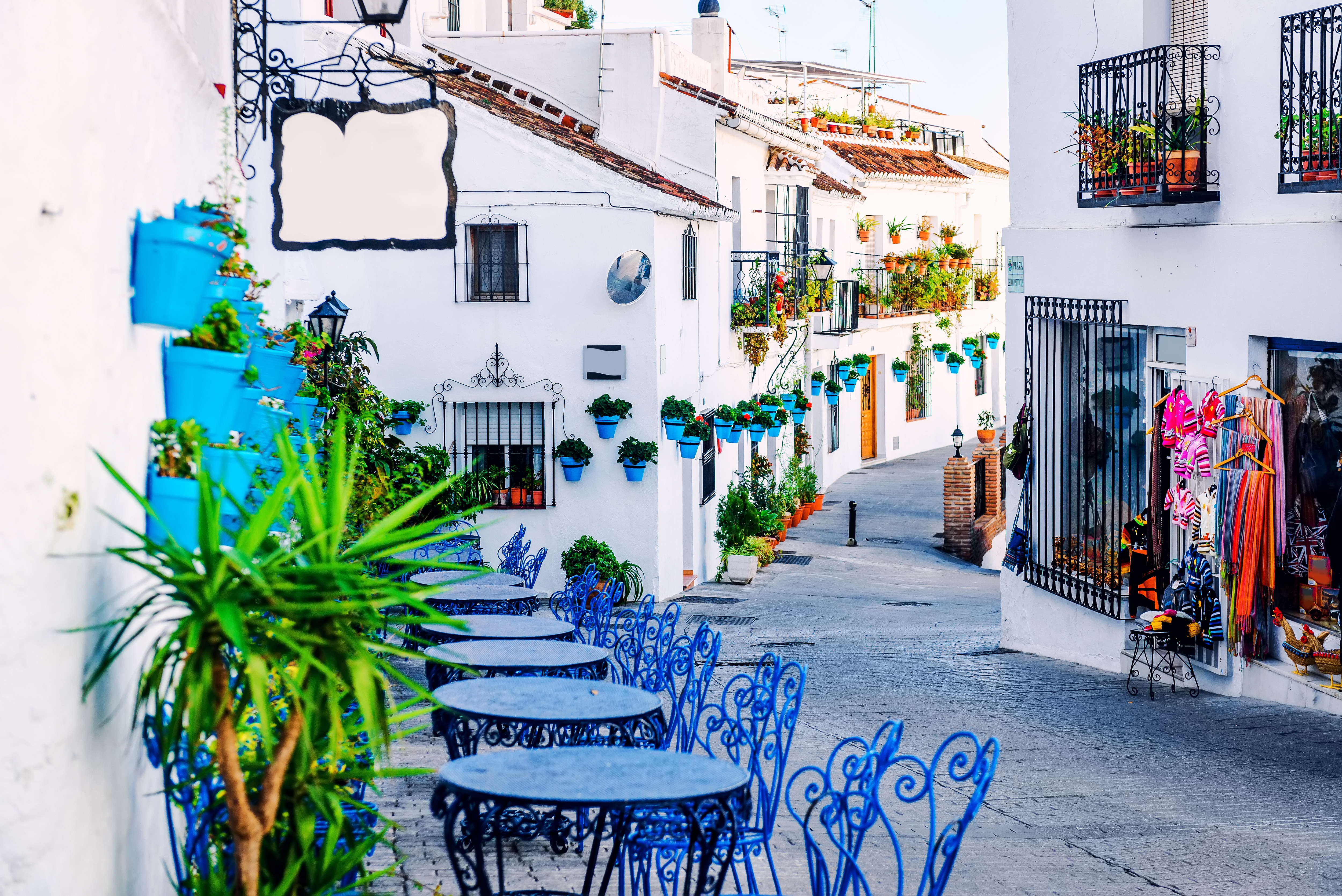 Karakteristisk hvid gade med blå blomsterkrukker i Mijas, en pittoresk bjergby i Andalusien, Spanien