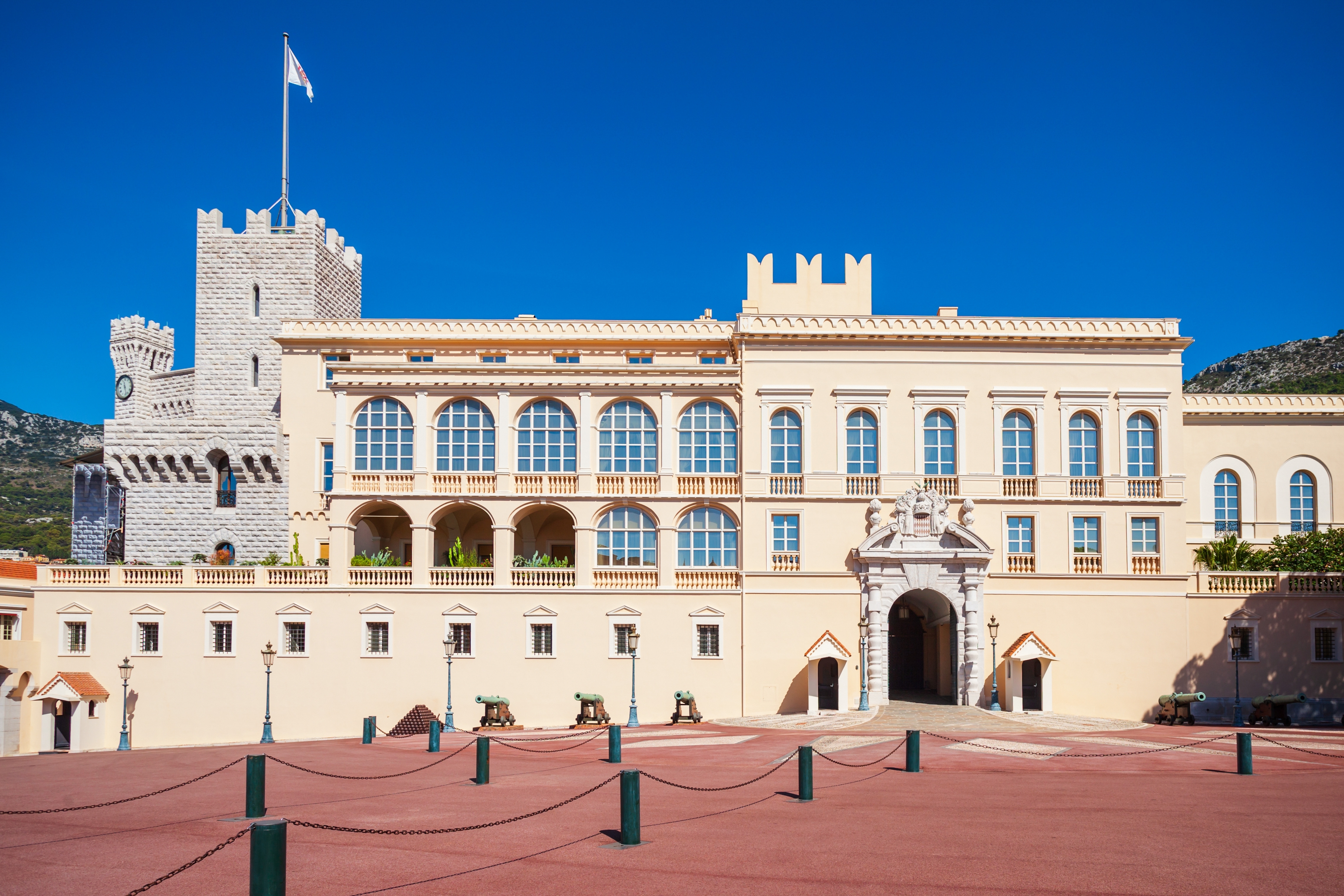 Det historiske fyrstepalads i Monaco med kanoner foran indgangen, kremfarvet facade og udsigt over Place du Palais på den franske Riviera