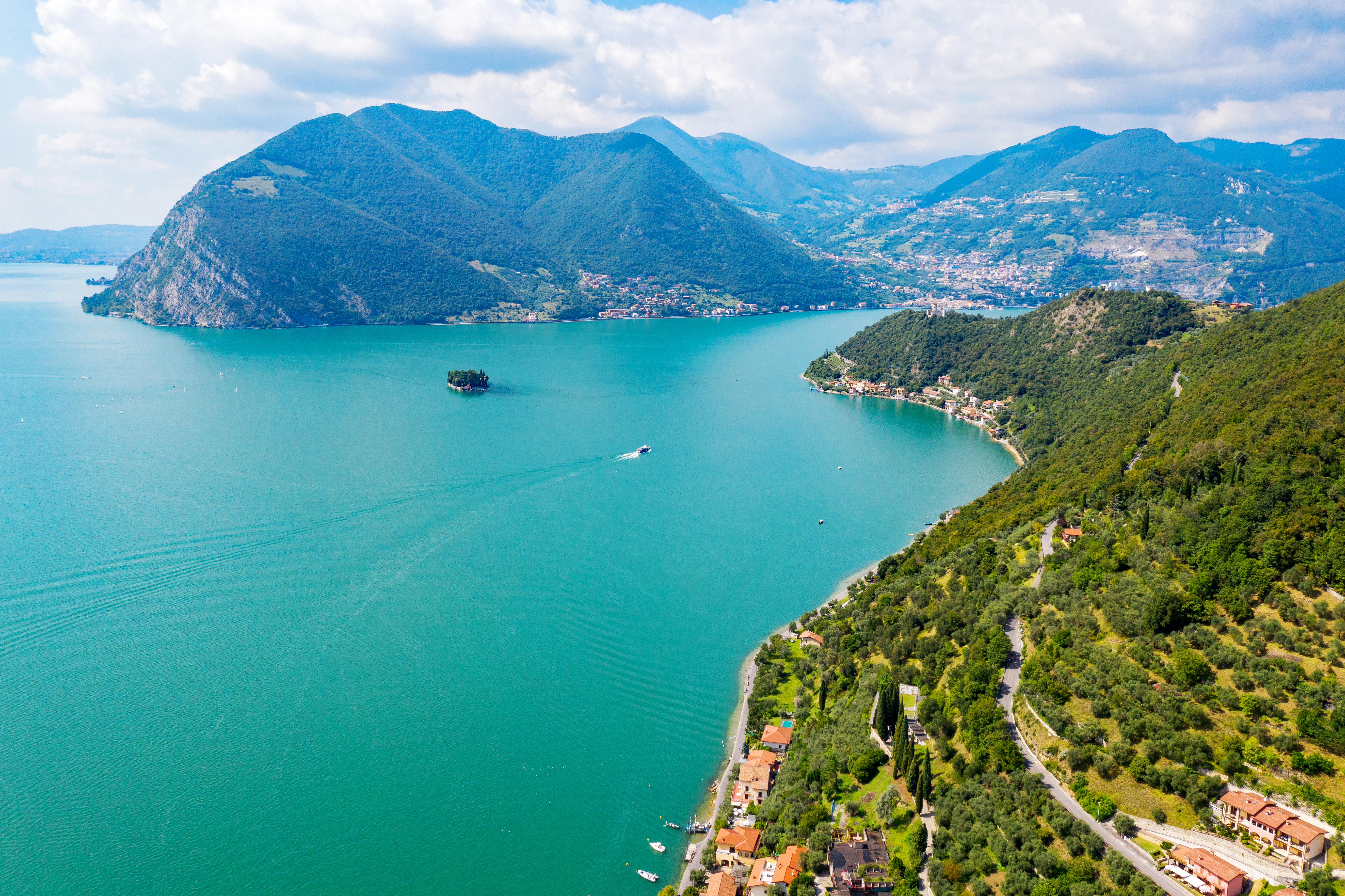 Luftfoto af Lago Iseo i Italien med det karakteristiske turkisblå vand, Monte Isola og den lille San Paolo-ø omgivet af frodig natur
