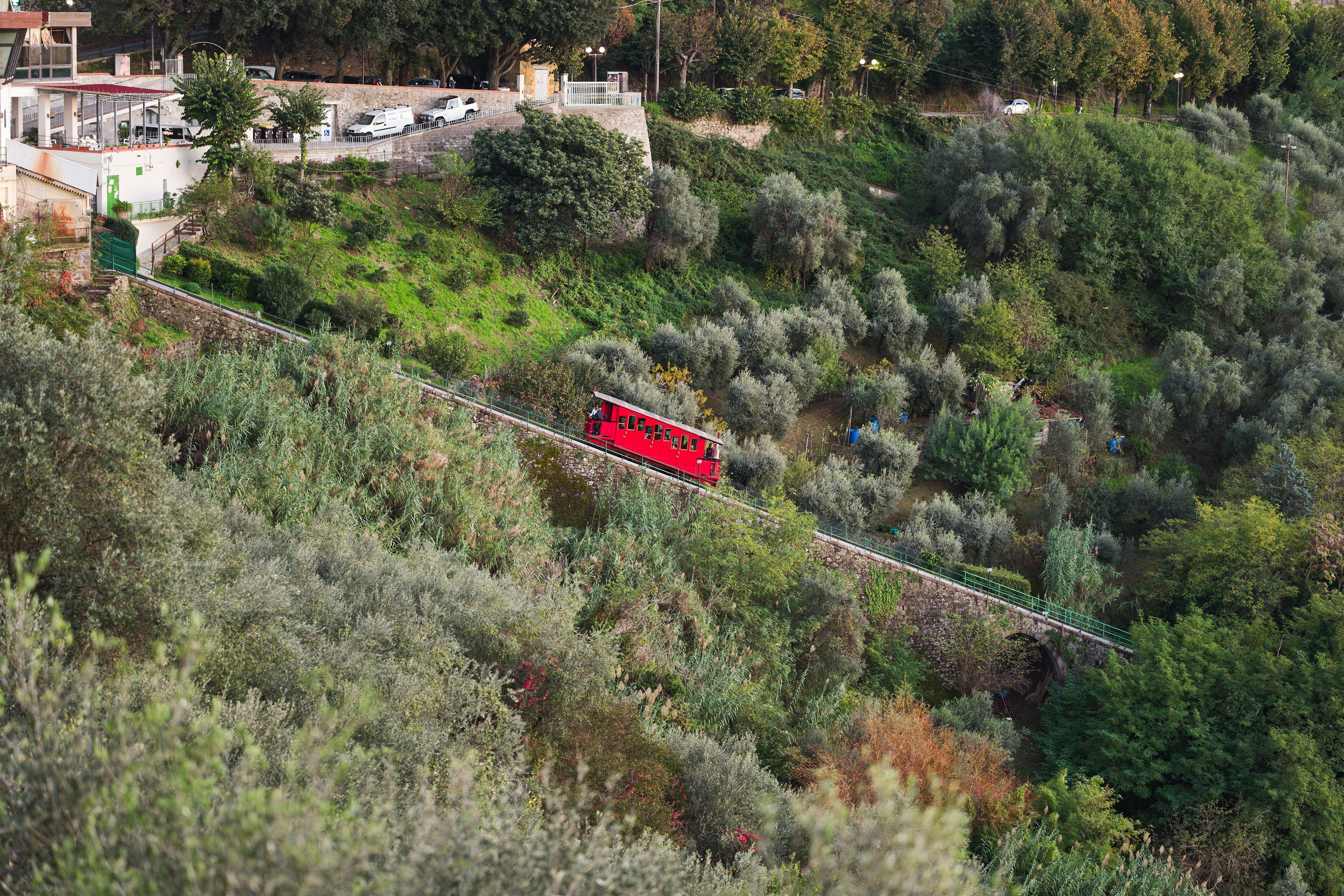 Udsigt over den røde funicular i Montecatini Terme der baner vej op gennem oliventræer til den charmerende middelalderby i Toscana