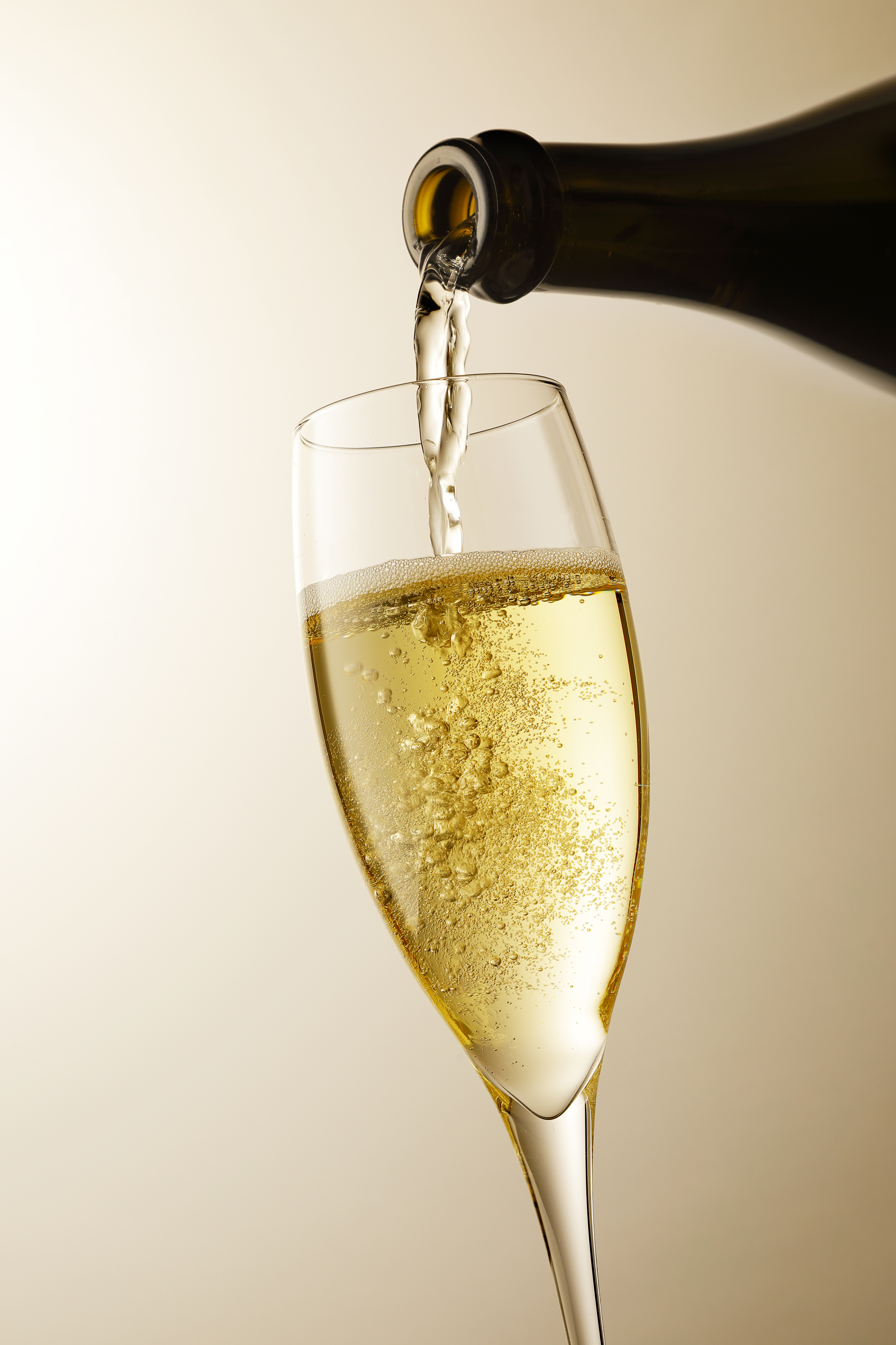 Gyldent champagneglas med mousserende vin og bobler der hældes til en festlig og uforglemmelig rejseoplevelse
